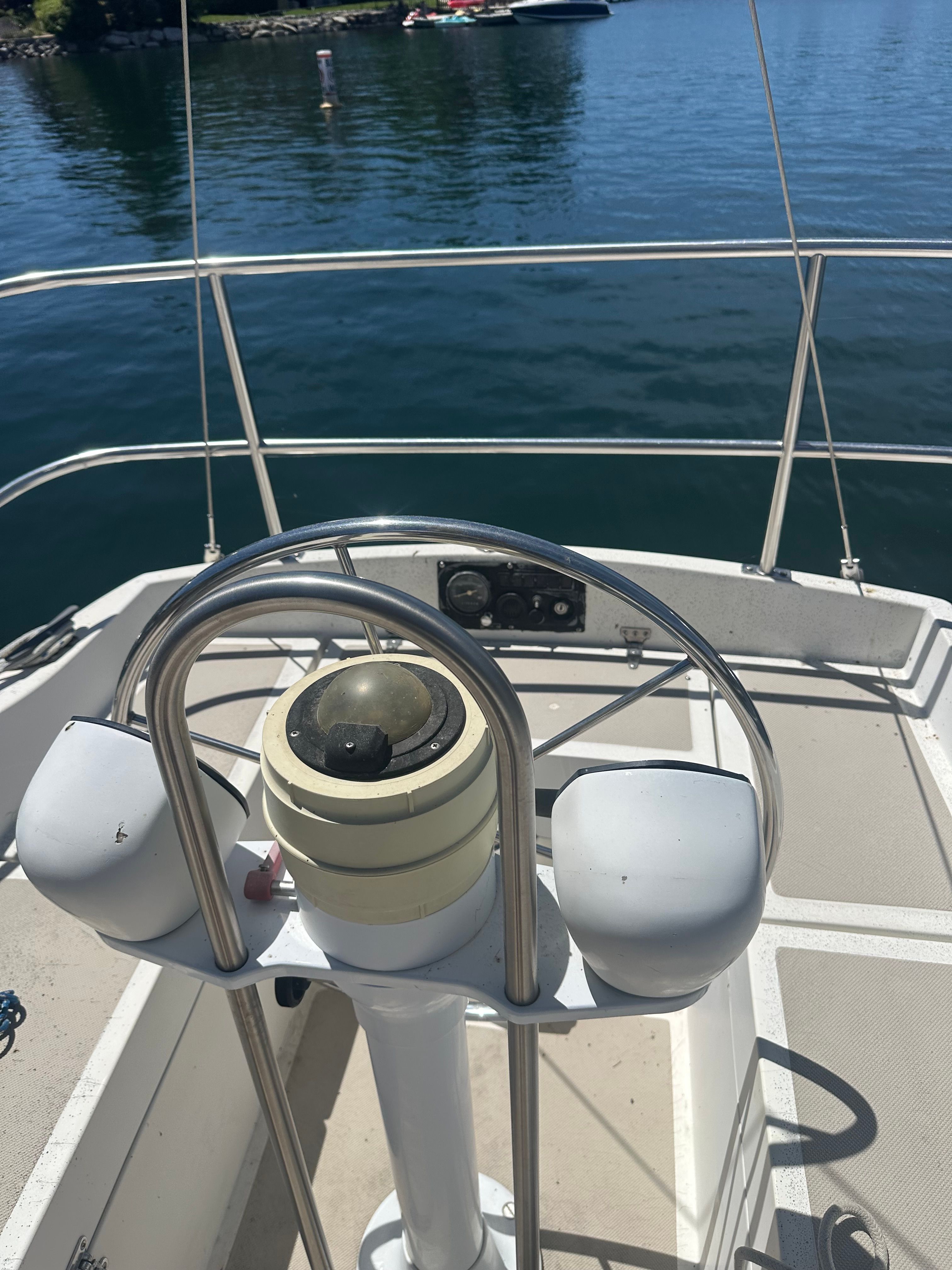 The cockpit of a 1982 Lancer 30 yacht with a steering wheel and calm water in the background.
