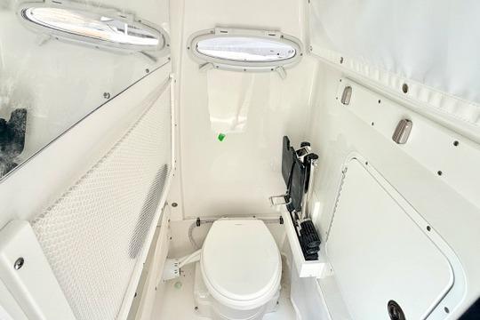 2026 Sea Hunt Ultra 255 SE boat interior with compact marine toilet and storage.
