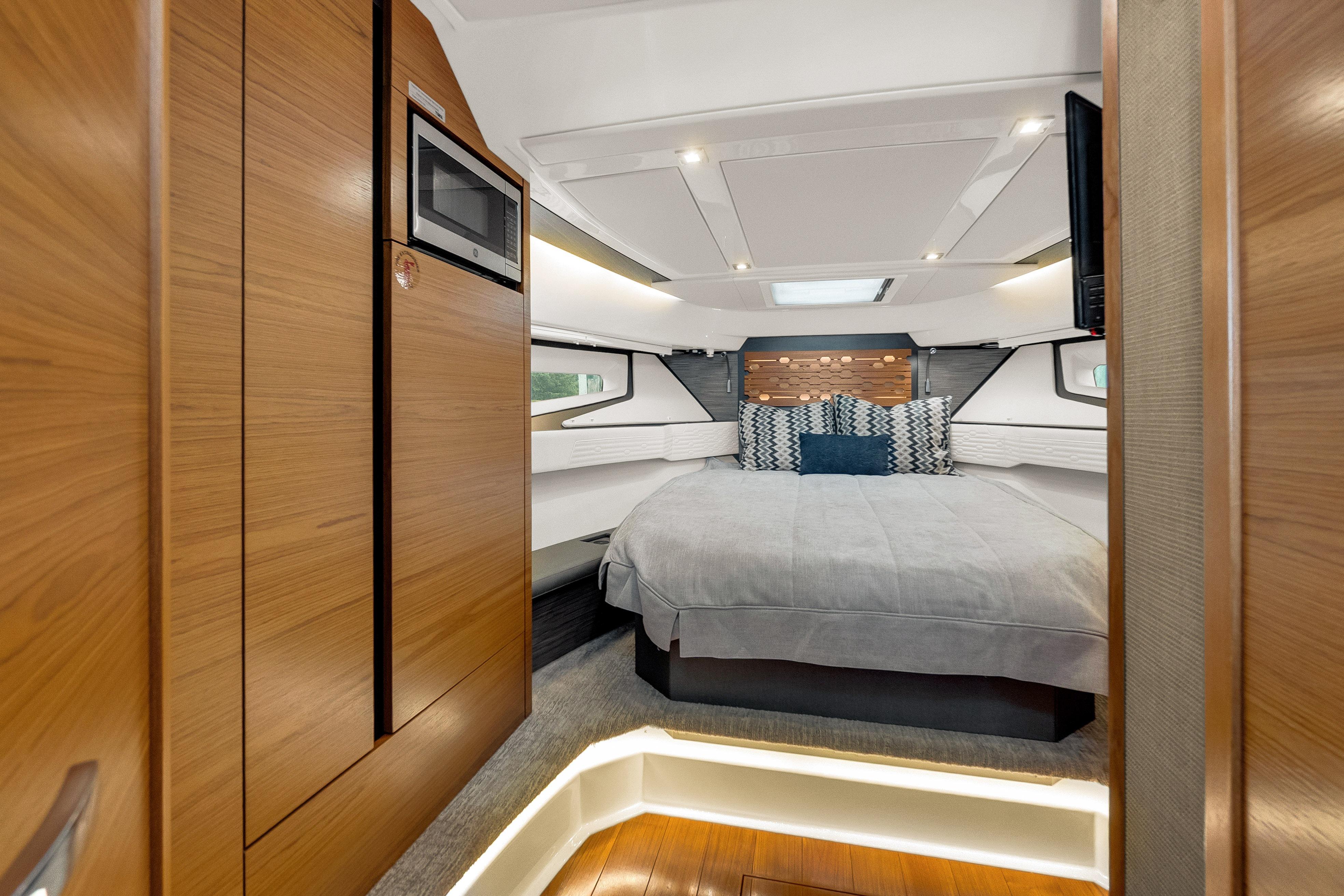 Luxurious interior of 2021 Tiara Sport 43 LE yacht with cozy bed and modern wood finishes.