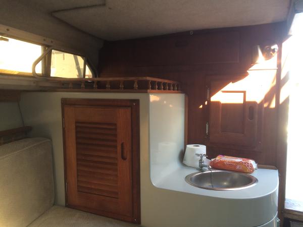 1987 Boston Whaler Cuddy Tower interior with sink, wooden cabinet, and seating area.