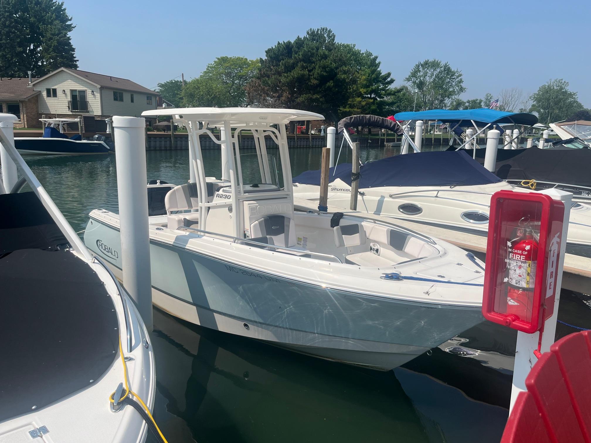 2020 Robalo R230 Center Console boat docked in a marina, surrounded by other boats.