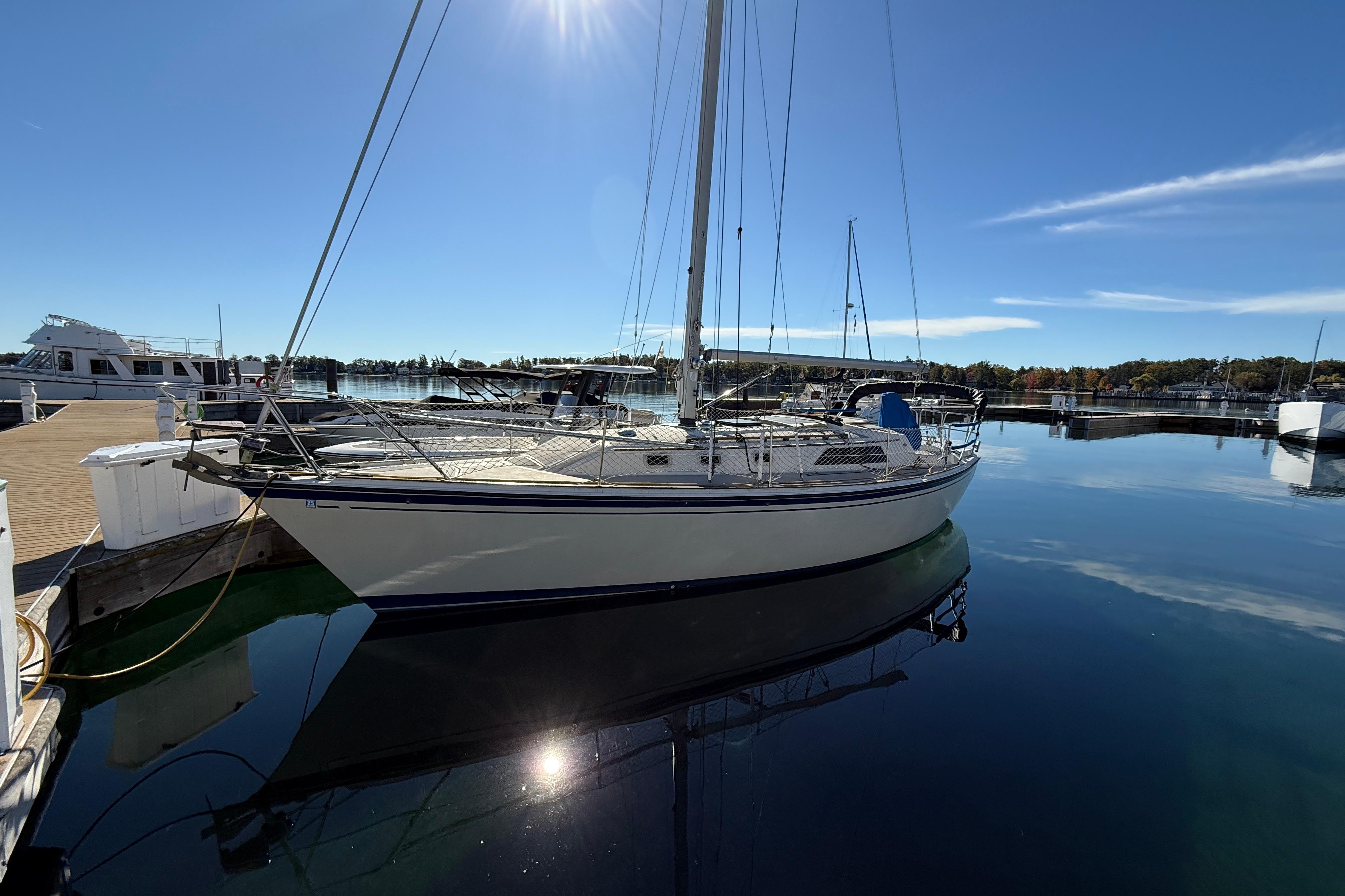 1983 O'Day 34 sailboat docked in a serene marina under clear blue skies.