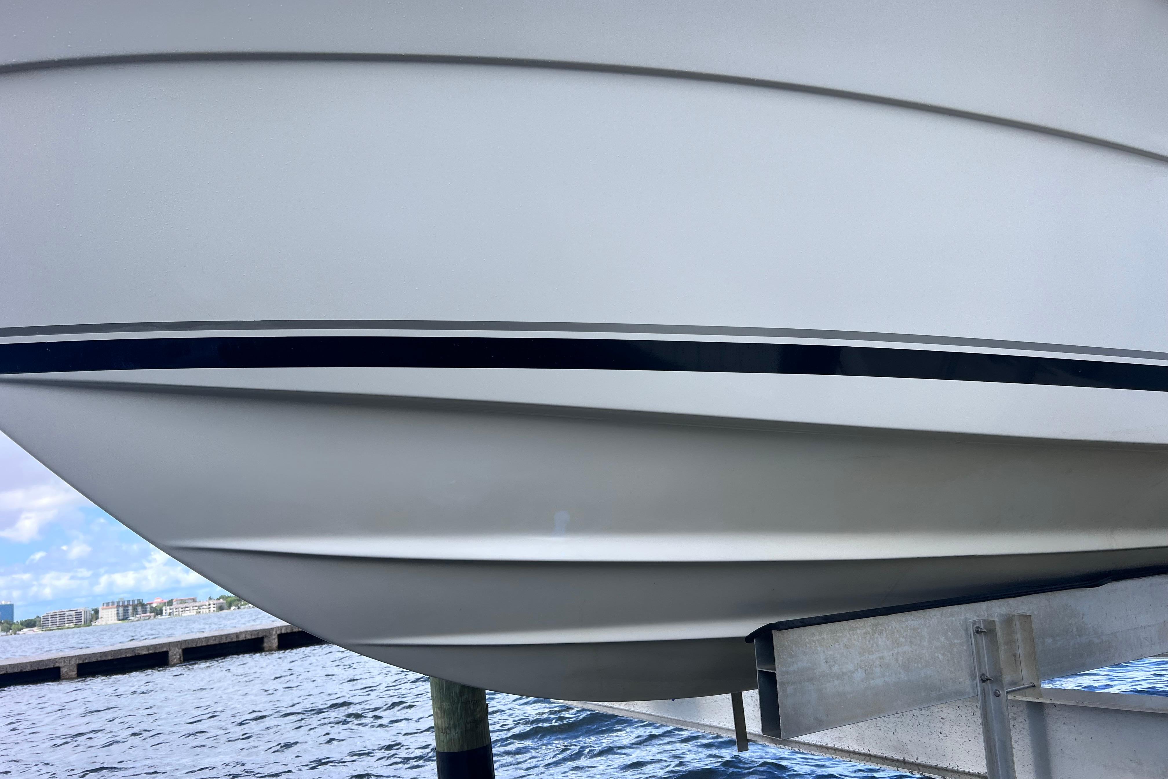 2004 Pursuit 2870 Walkaround boat hull on lift by waterfront.