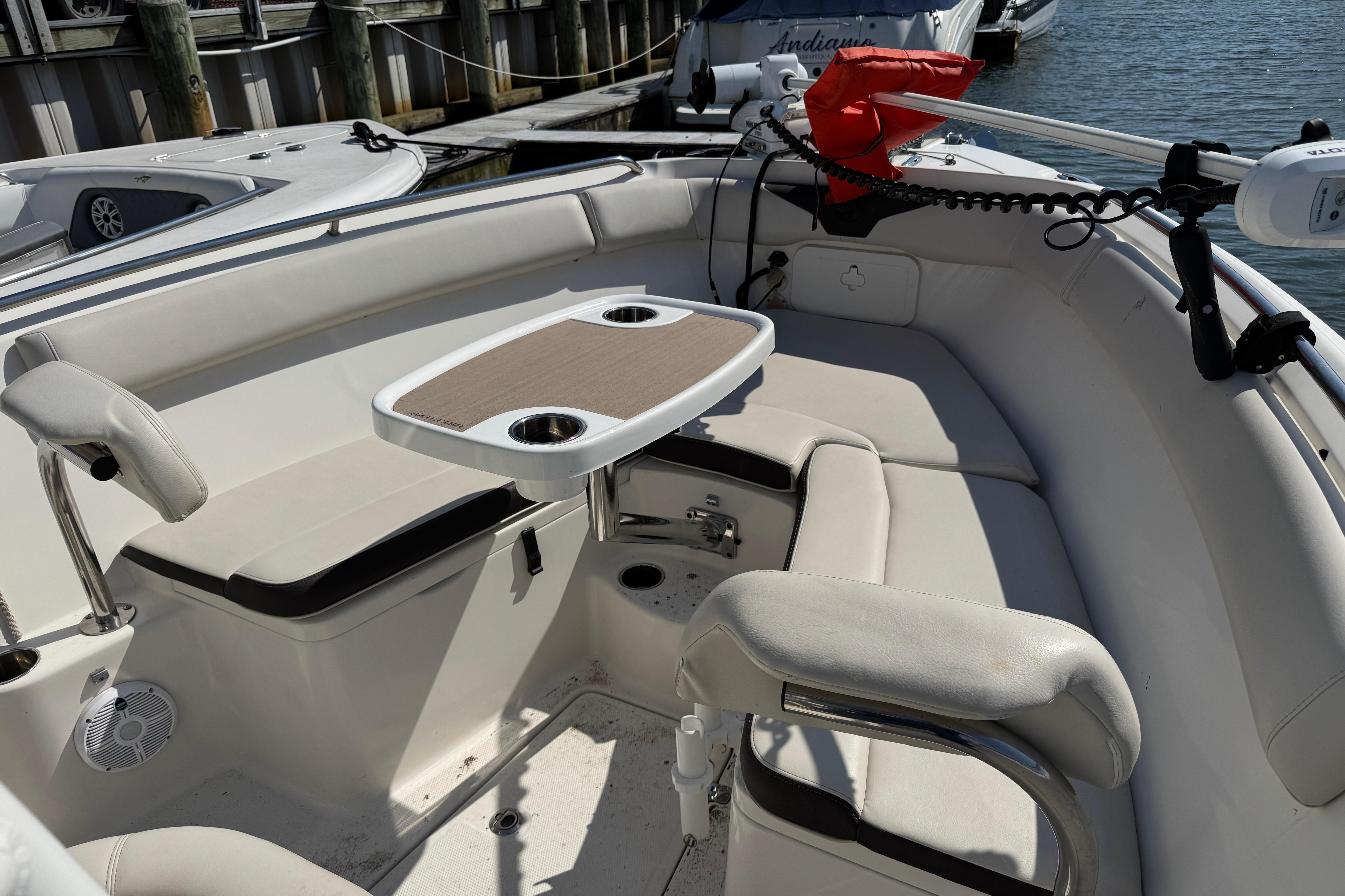 Interior of 2022 Sailfish 242 CC boat with seating and table, docked at marina.