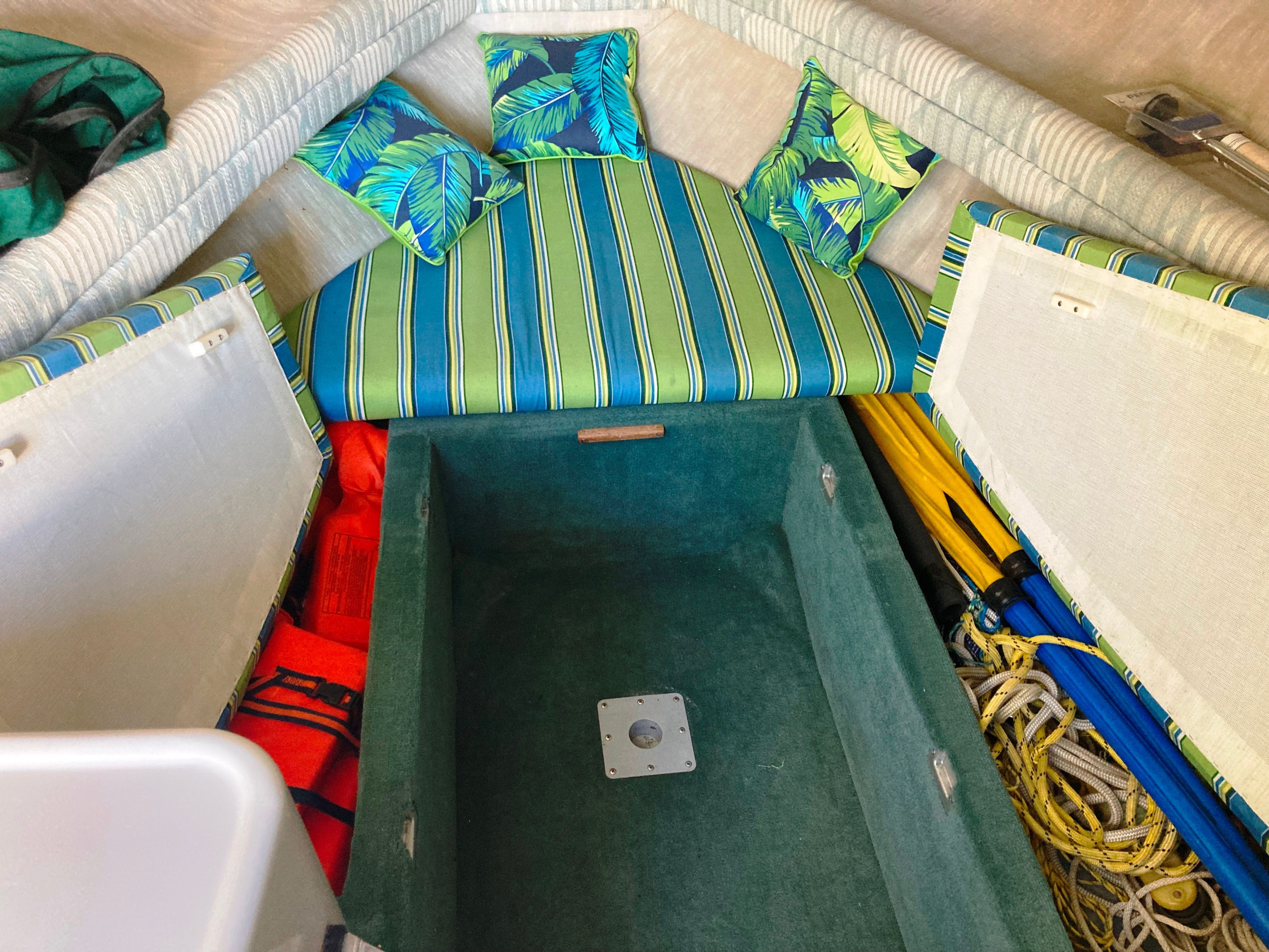 The image shows the interior of a 1991 Sea Ray 220 Sundancer with colorful cushions and storage space.