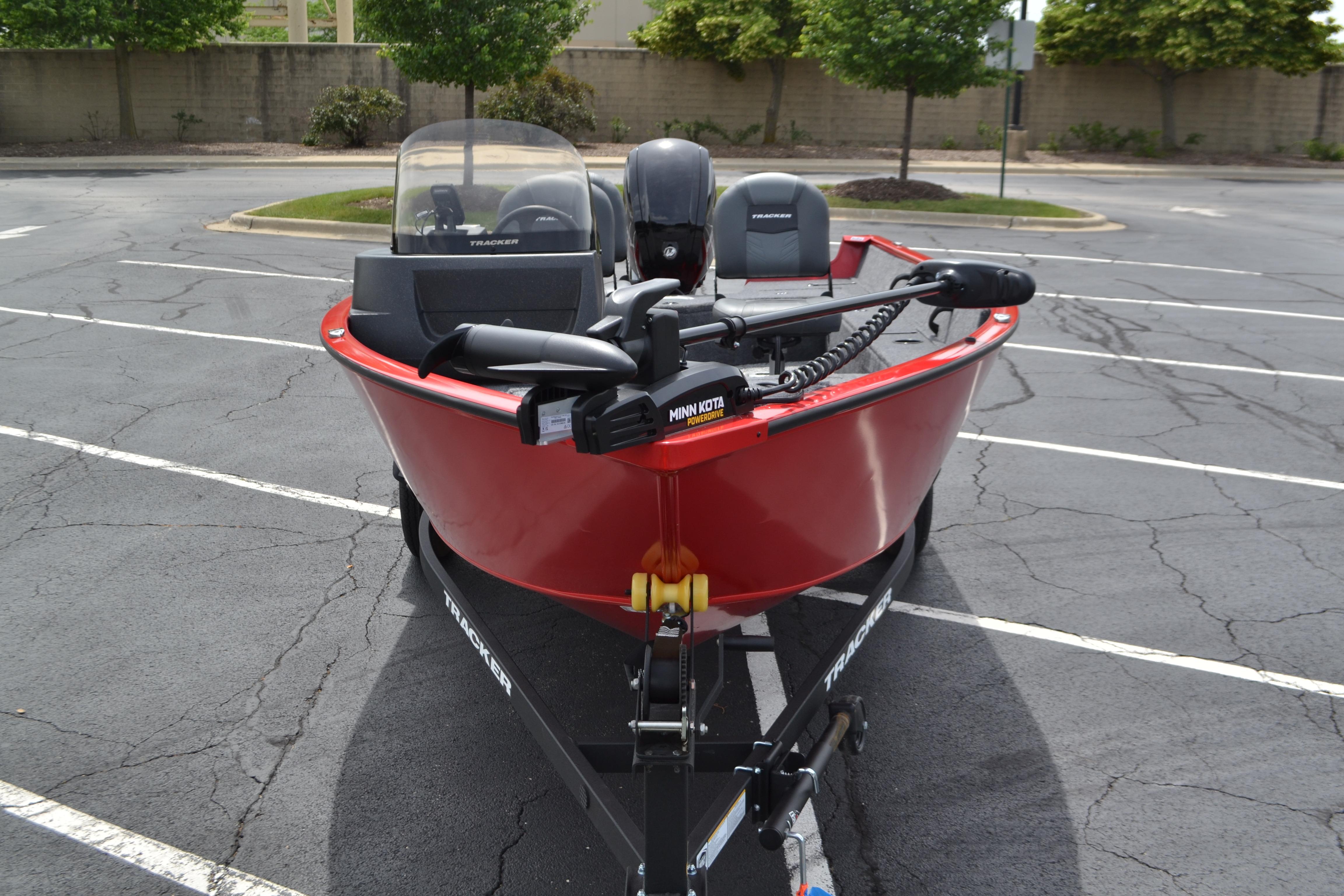 2026 Tracker Pro Guide V-16 SC boat in a parking lot, featuring a red hull and trolling motor.
