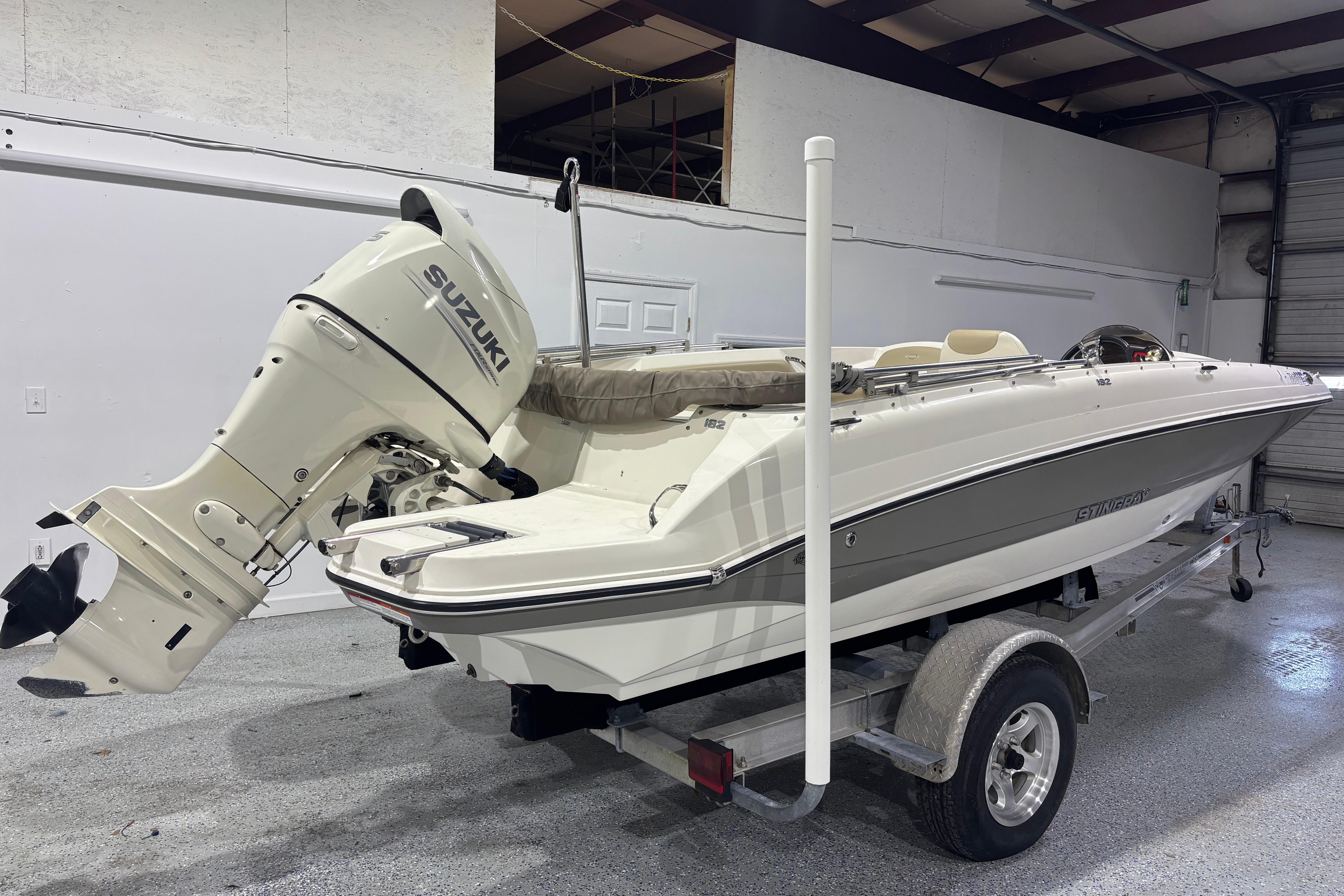 2017 Stingray 182 SC boat with Suzuki outboard motor on trailer in garage.