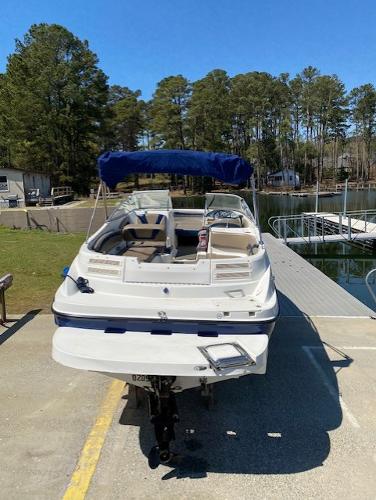2005 Bayliner 249 SD boat docked at a marina with trees in the background.