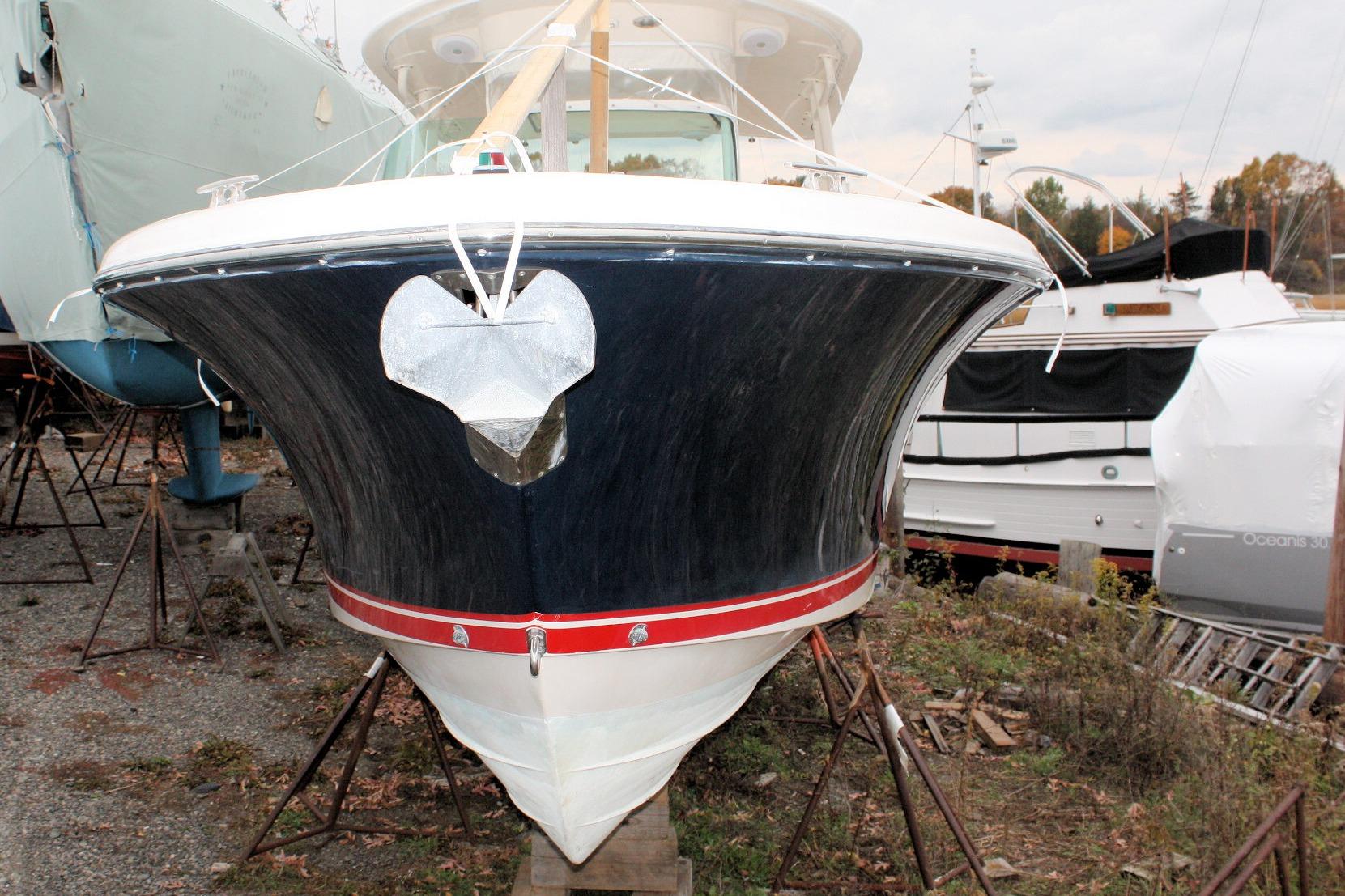 2013 Pursuit ST 310 Sport boat on stands, front view, in a marina setting.