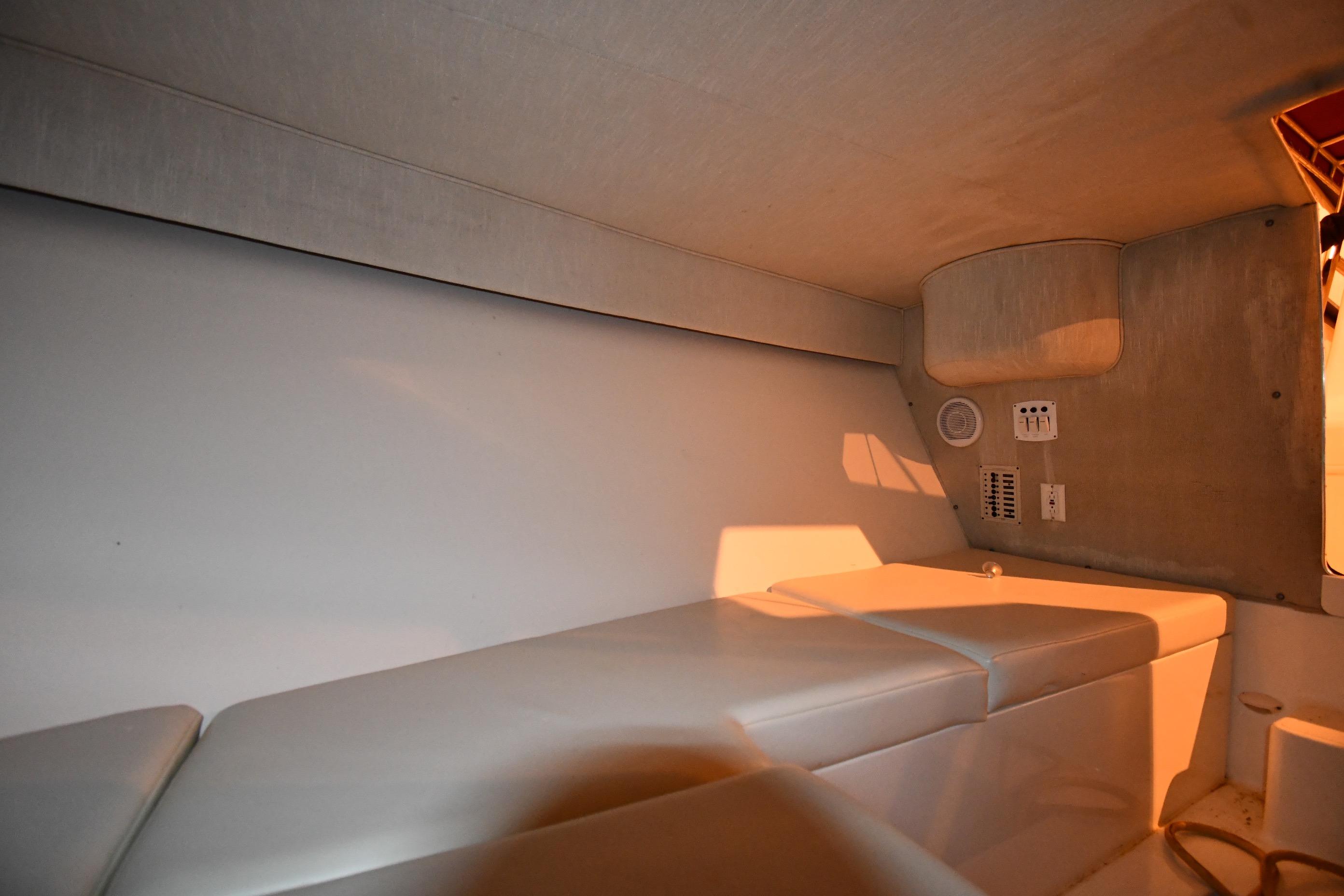 Interior cabin of 2001 Fountain 38 Center Console boat, featuring cushioned seating and control panel.