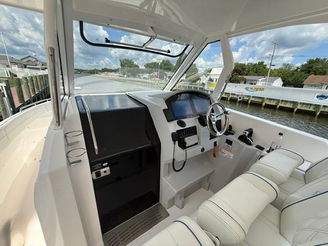 The cockpit of a modern yacht with helm and comfortable seating, docked by the water.