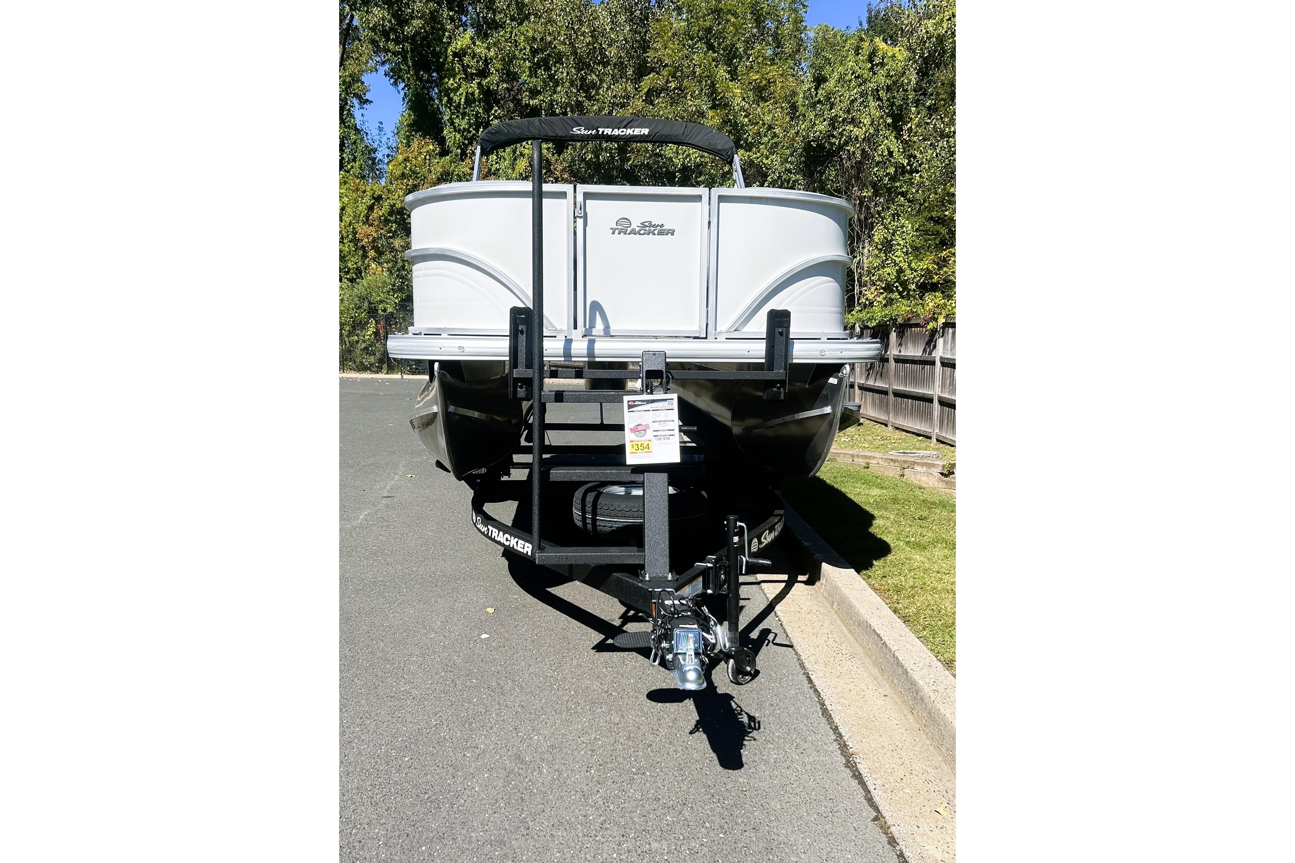 2026 Sun Tracker Party Barge 18 DLX pontoon boat on trailer, parked on a sunny street.