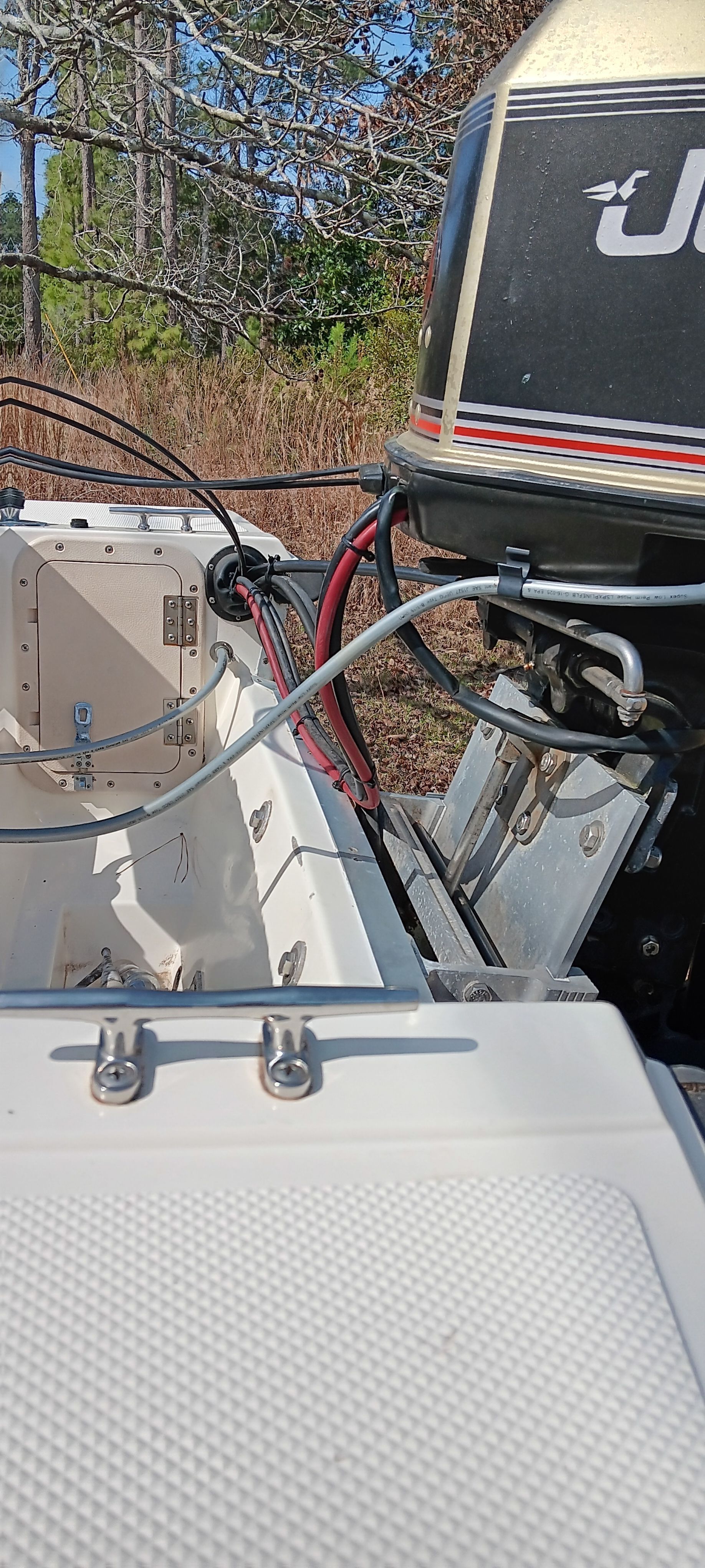 A 1990 Hydra-Sports Vector with an outboard motor, parked on dry land, surrounded by trees.