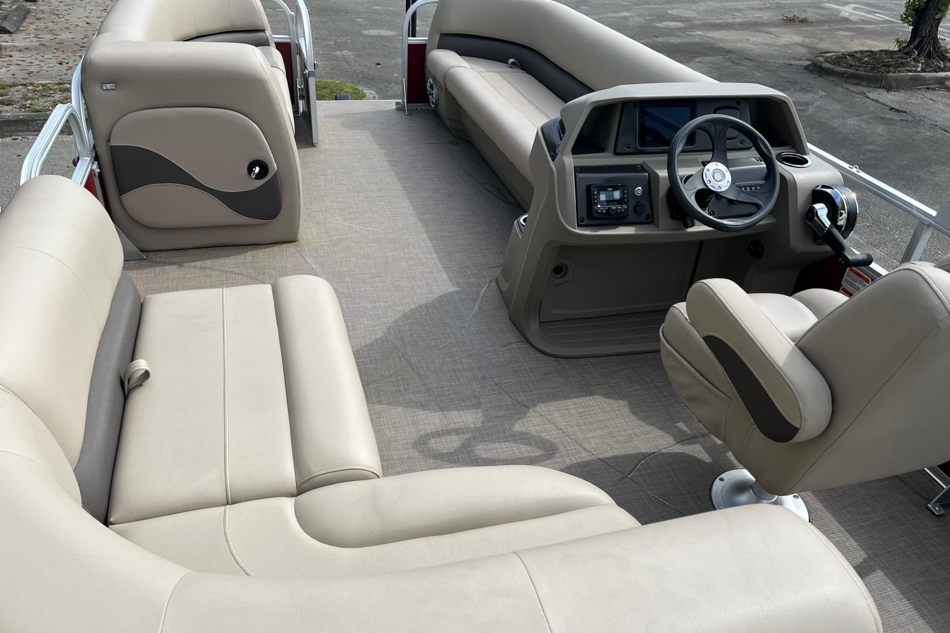 2025 Sun Tracker Party Barge 18 DLX interior with beige seating and modern helm.