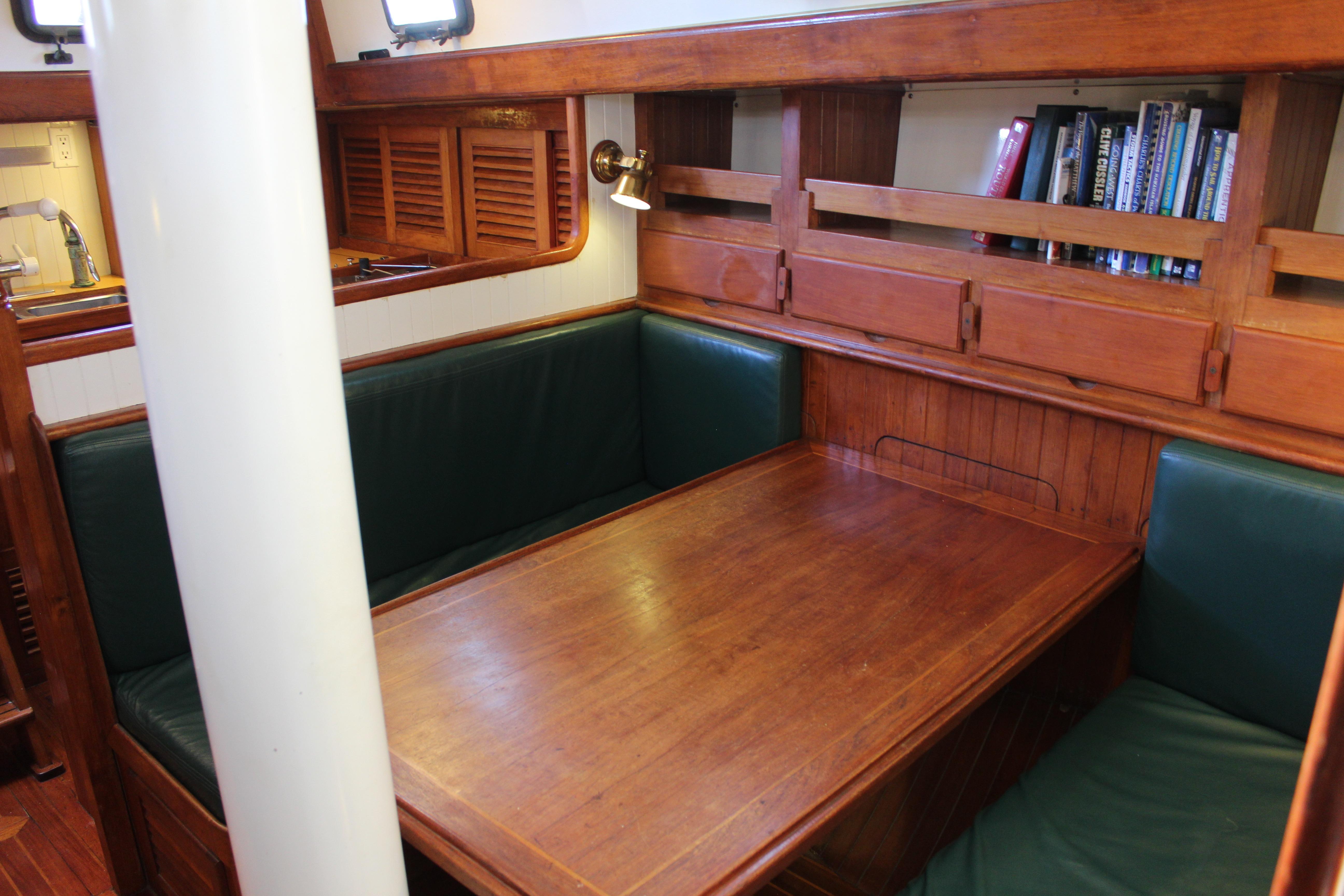 Interior of 1981 Kelly Peterson 46 sailboat with wooden dining area and green cushioned seating.
