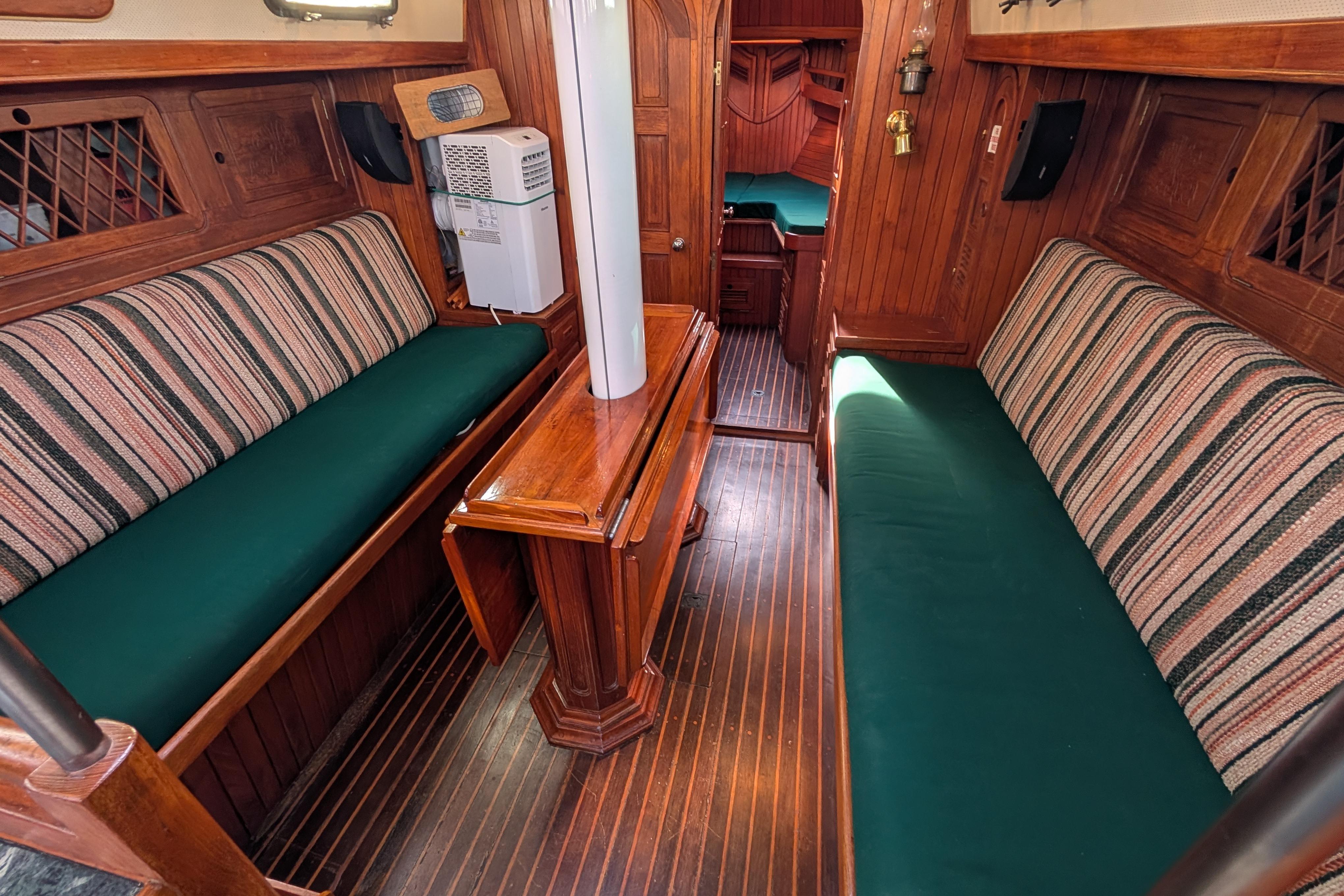 Interior of 1983 Robert Perry 41 sailboat with wooden furnishings and green cushions.