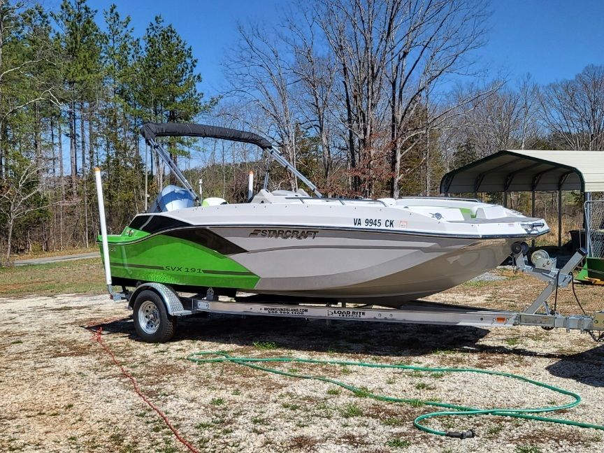A 2023 Starcraft SVX 191 OB boat on a trailer, featuring a green and white design, outdoors.