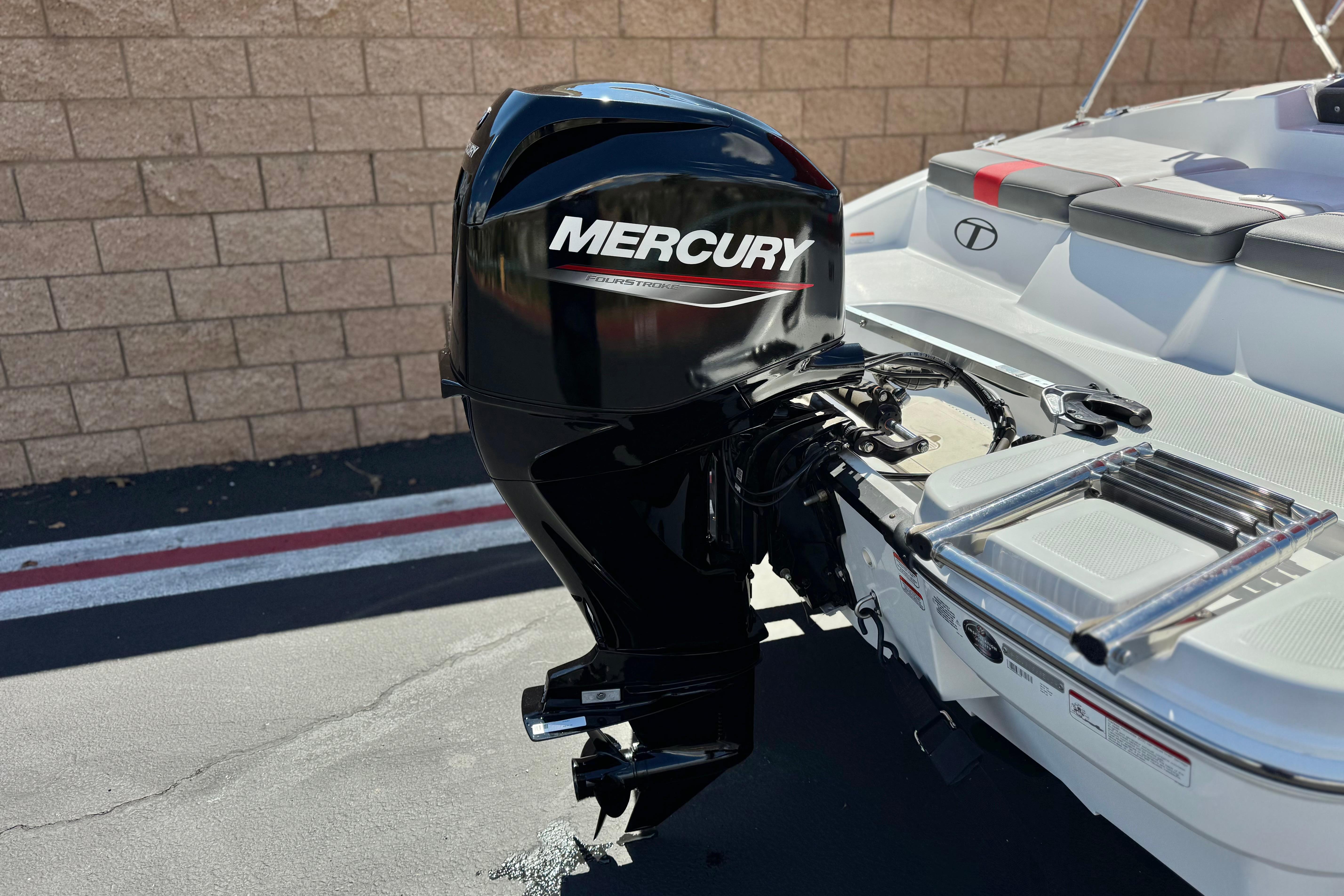 2024 Tahoe T16 boat with Mercury outboard motor, parked near a brick wall.