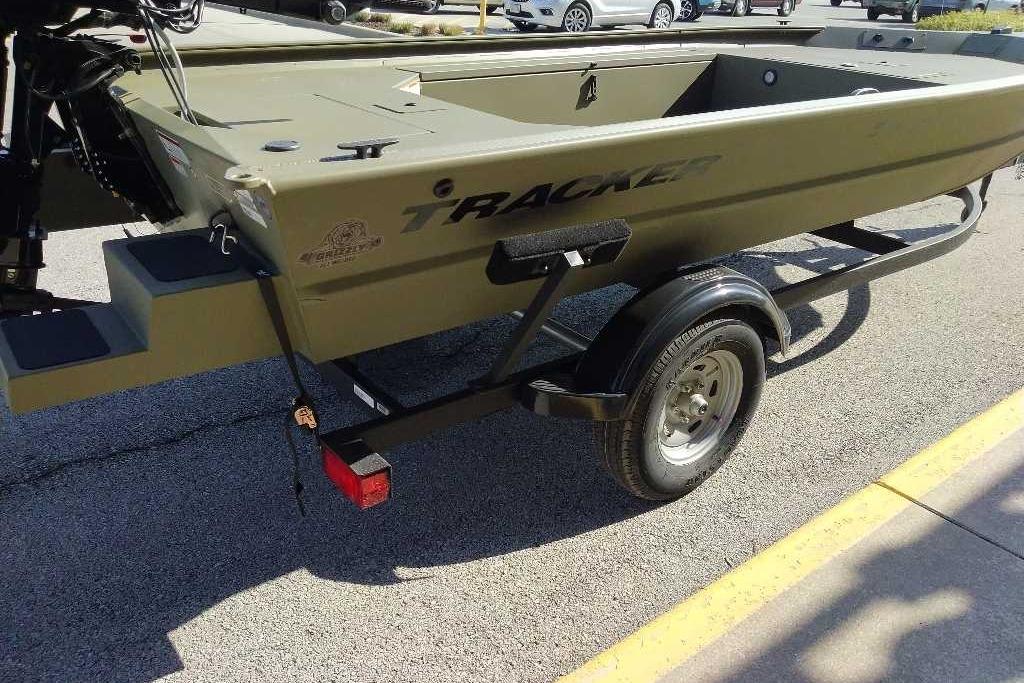 2026 Tracker Grizzly 1654 T Sportsman boat on trailer, parked on pavement.