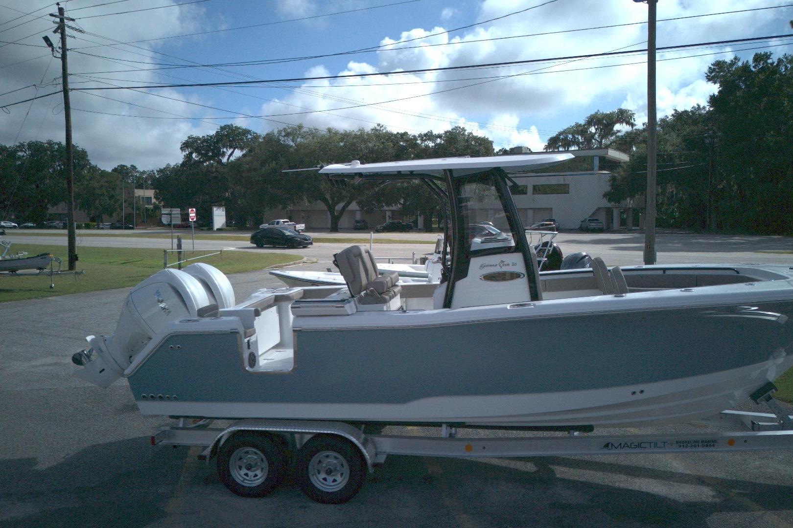 2026 Sea Hunt Gamefish 25 boat on trailer, parked outdoors under a partly cloudy sky.