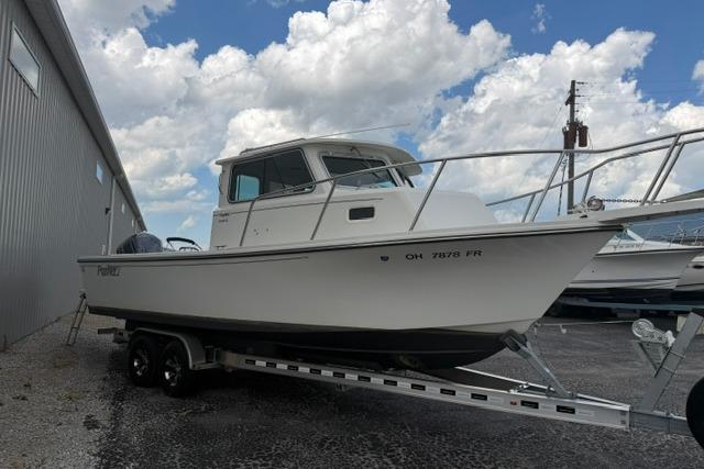 2016 Parker 2520 Sport Cabin boat on trailer, parked outdoors under a cloudy sky.
