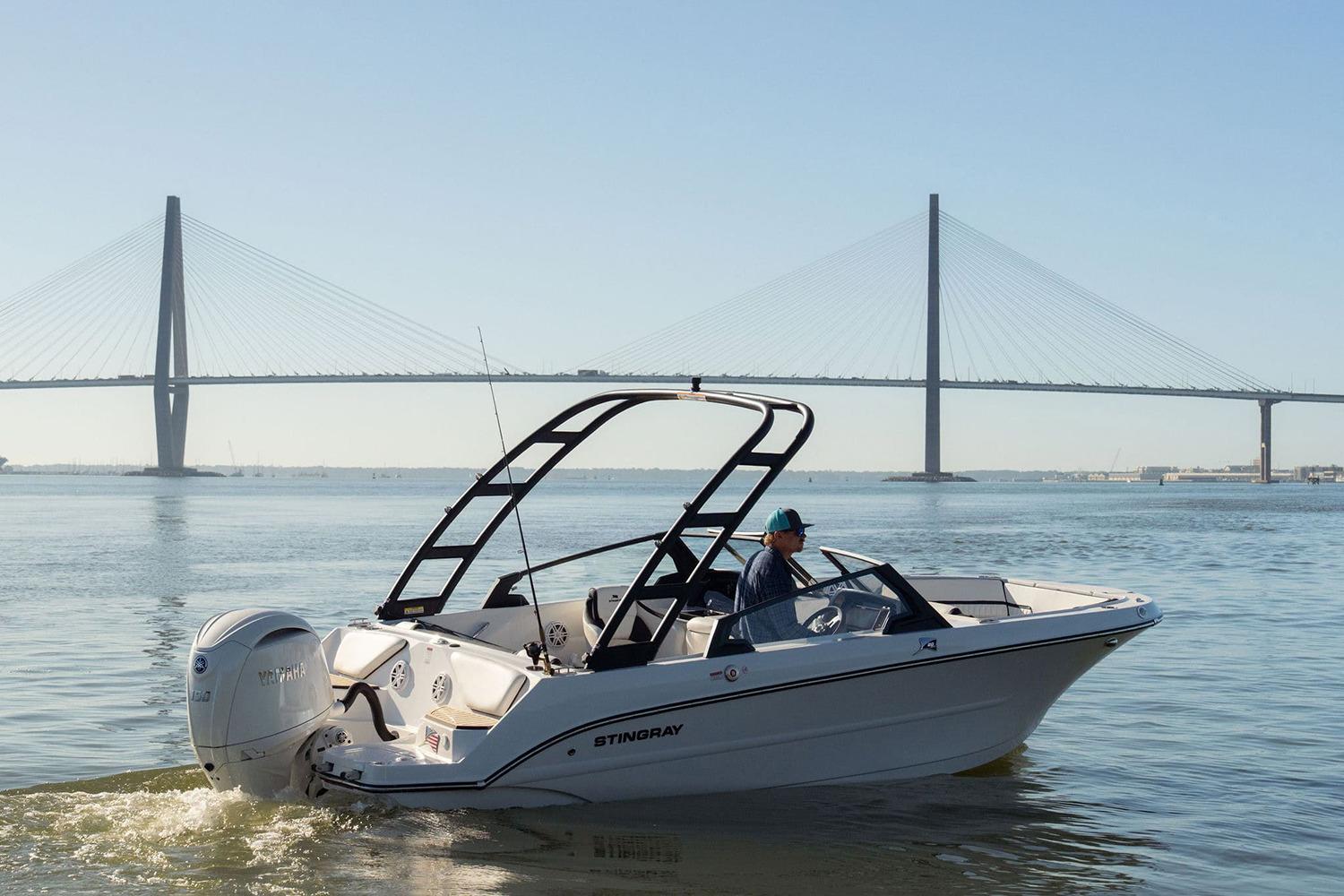 Manufacturer Provided Image: 2026 Stingray 20 SBX boat cruising near a large suspension bridge on a sunny day.