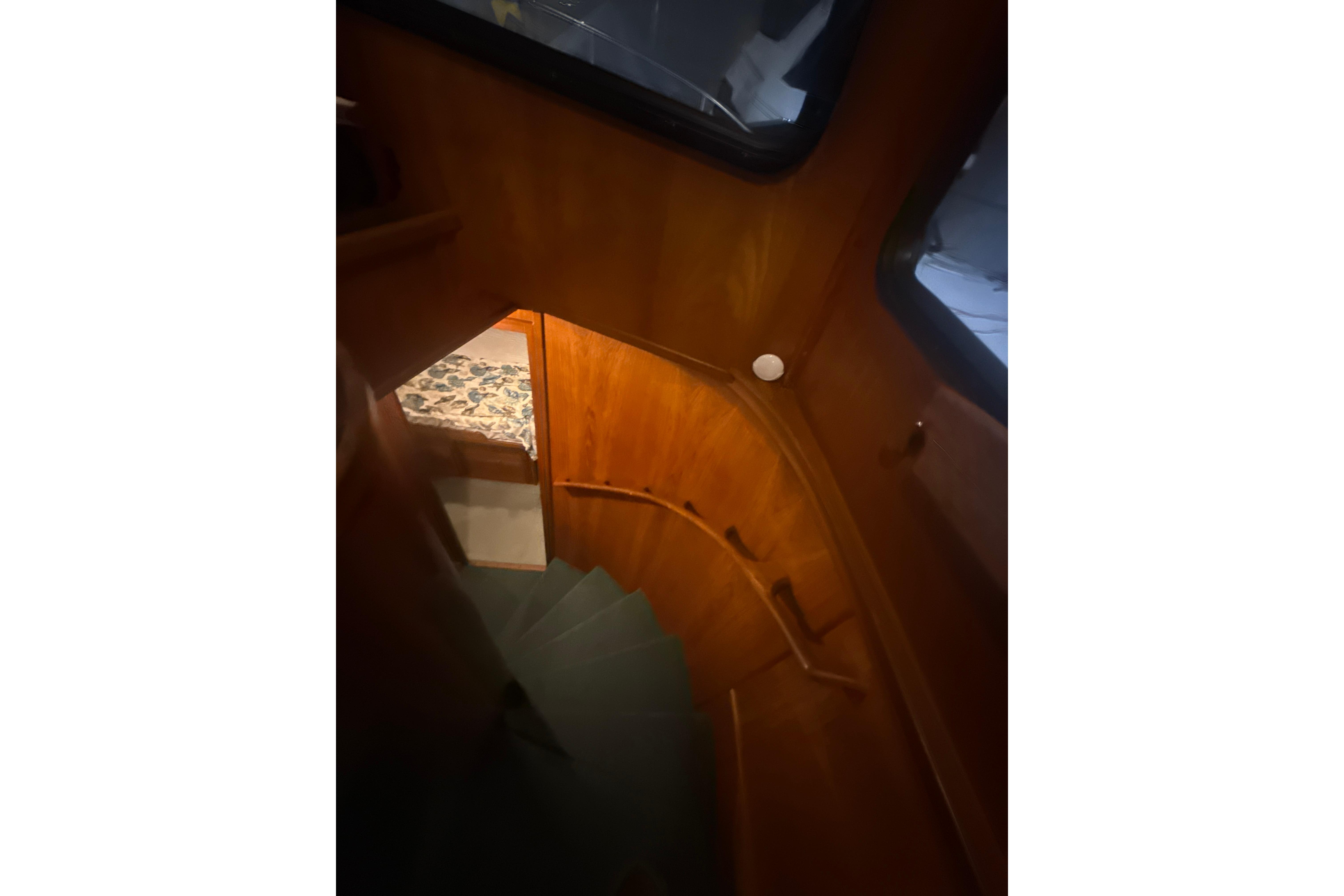 Staircase inside 1997 Nordic Tug 42, featuring wooden interior and cozy lighting.