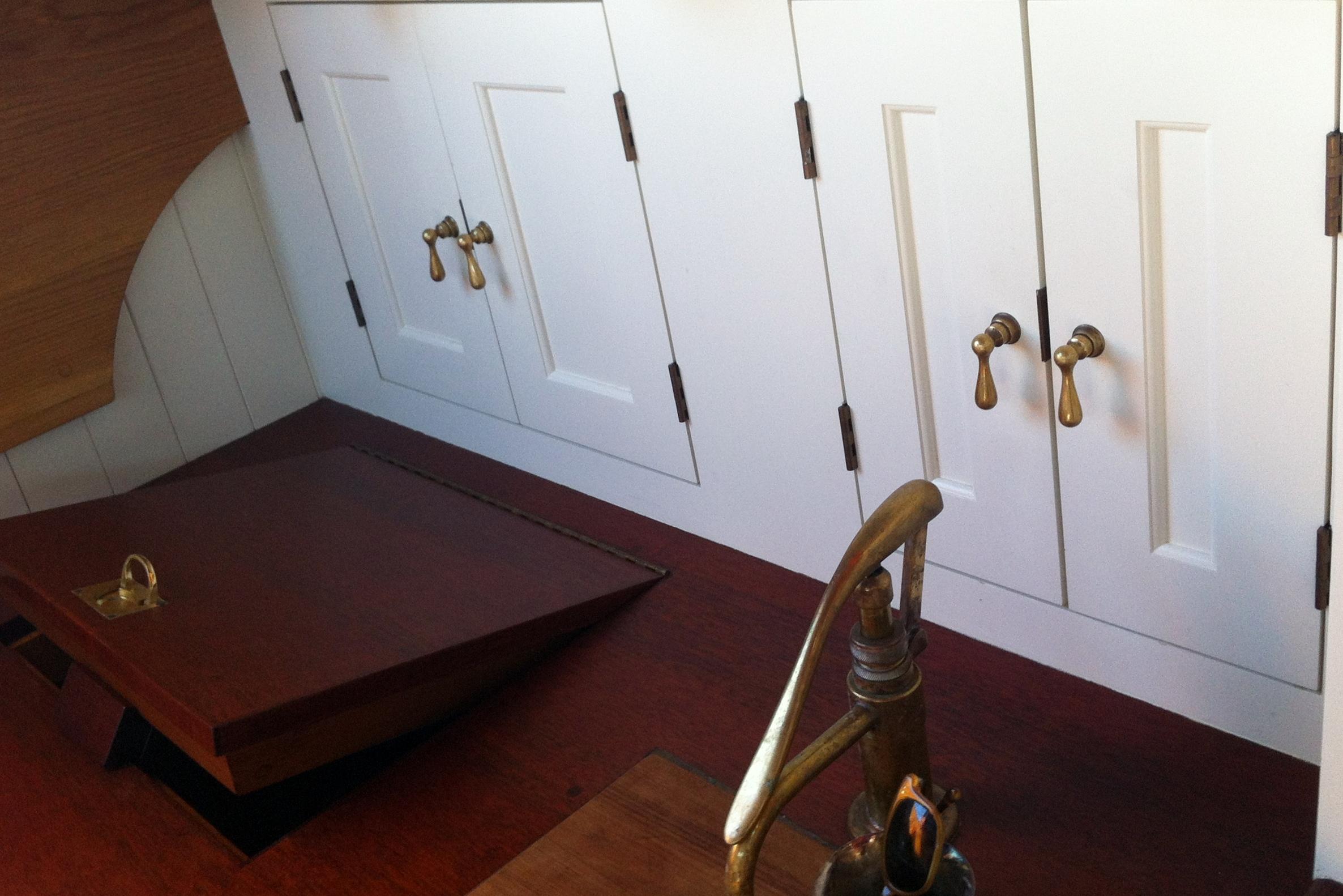 Interior of 1902 Herreshoff Gaff Cutter with brass fixtures and wooden cabinetry.