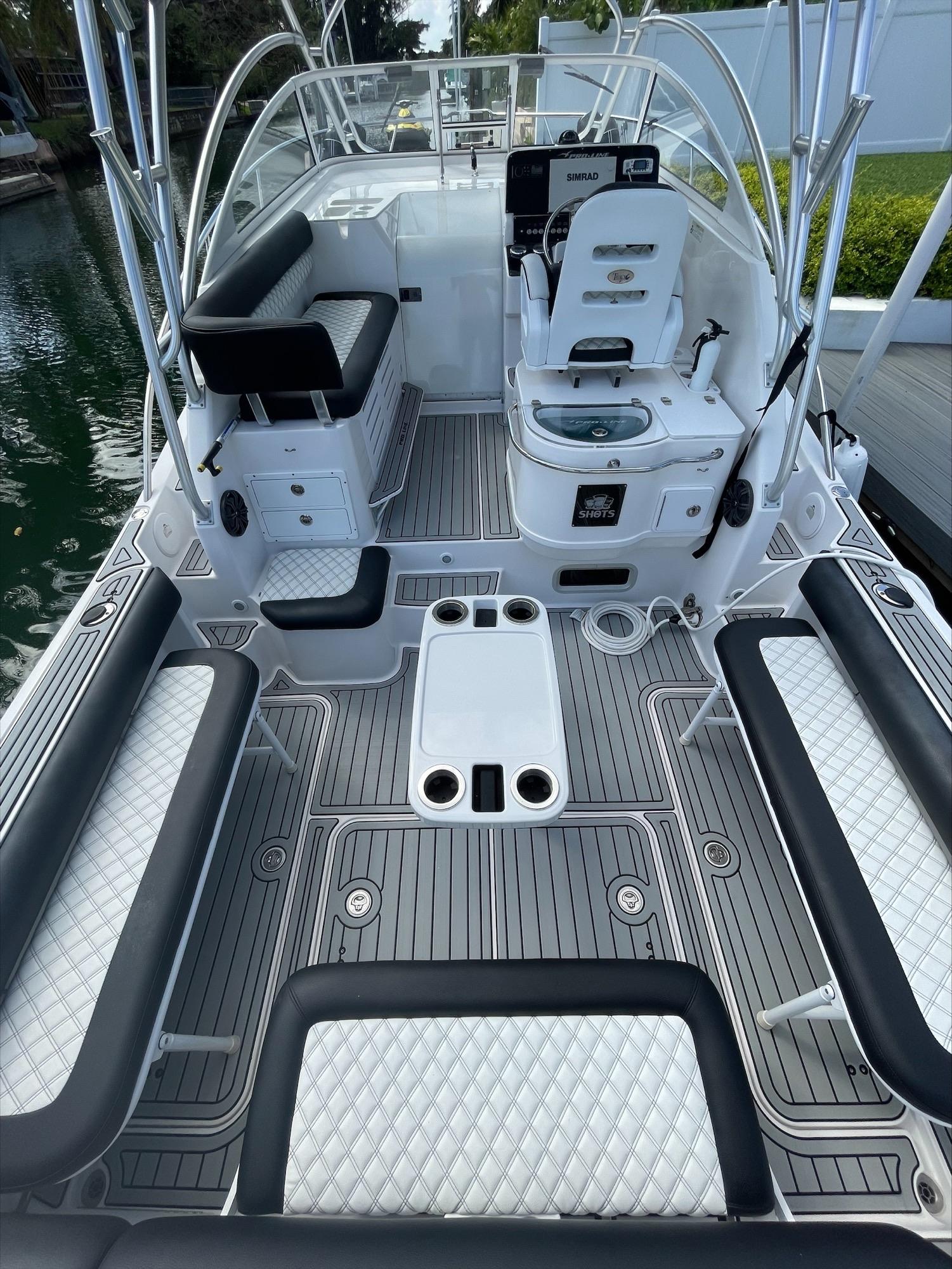 The boat features a spacious deck with seating benches and a helm station.