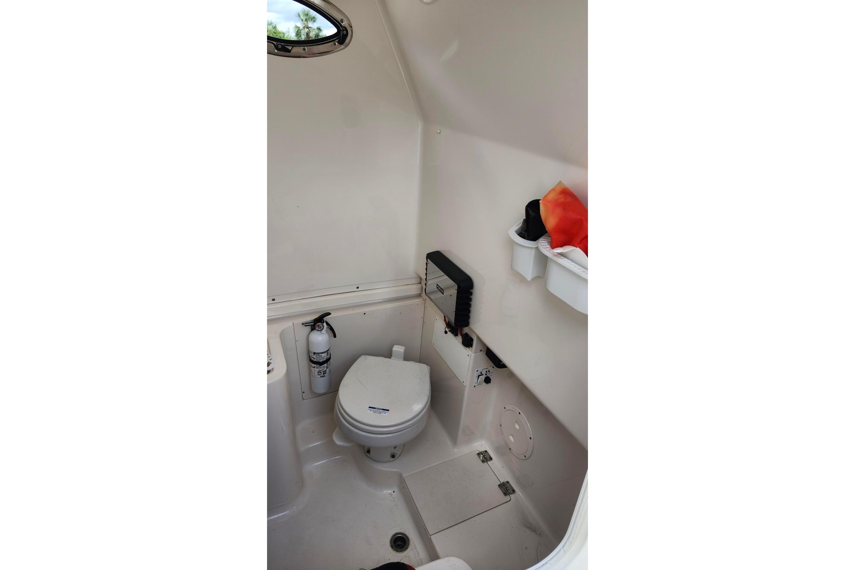 2015 Robalo R300 Center Console boat interior with toilet and storage shelves.