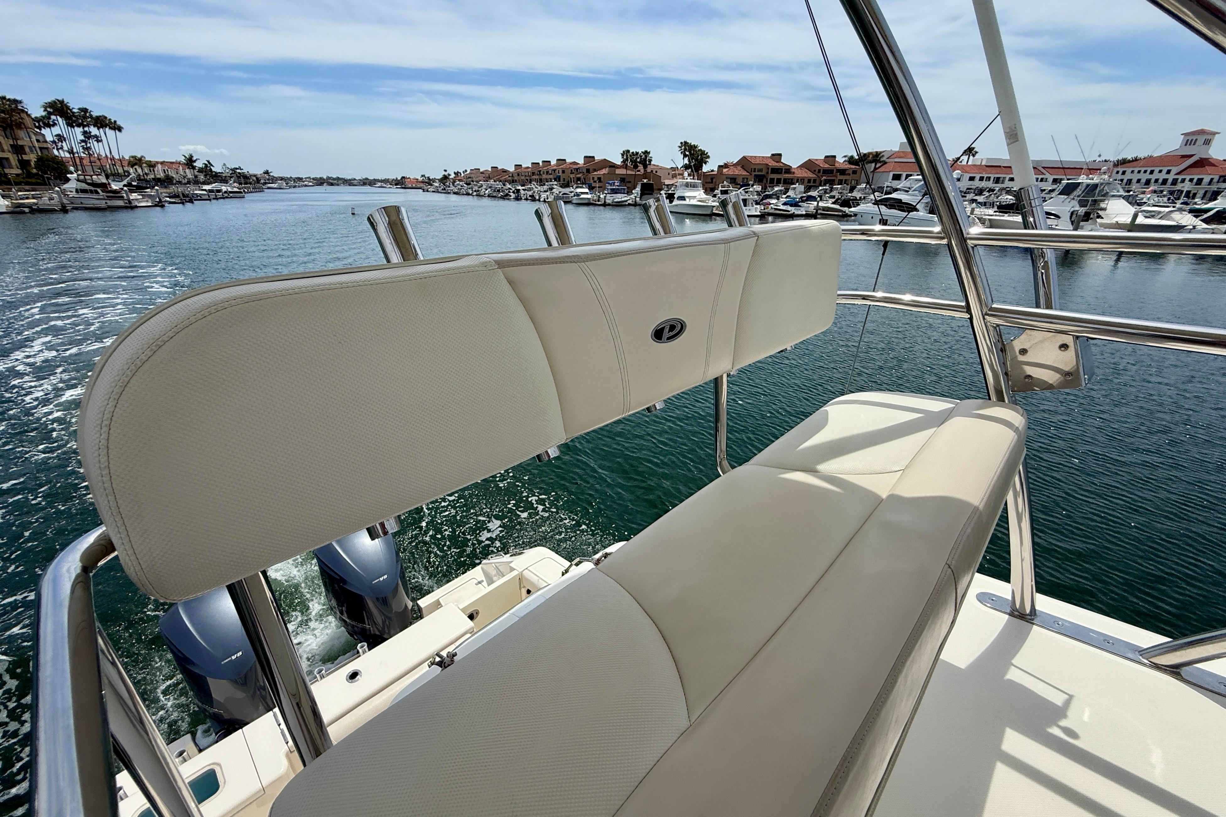 2012 Pursuit OS 345 Offshore boat with beige seating, cruising in a marina.