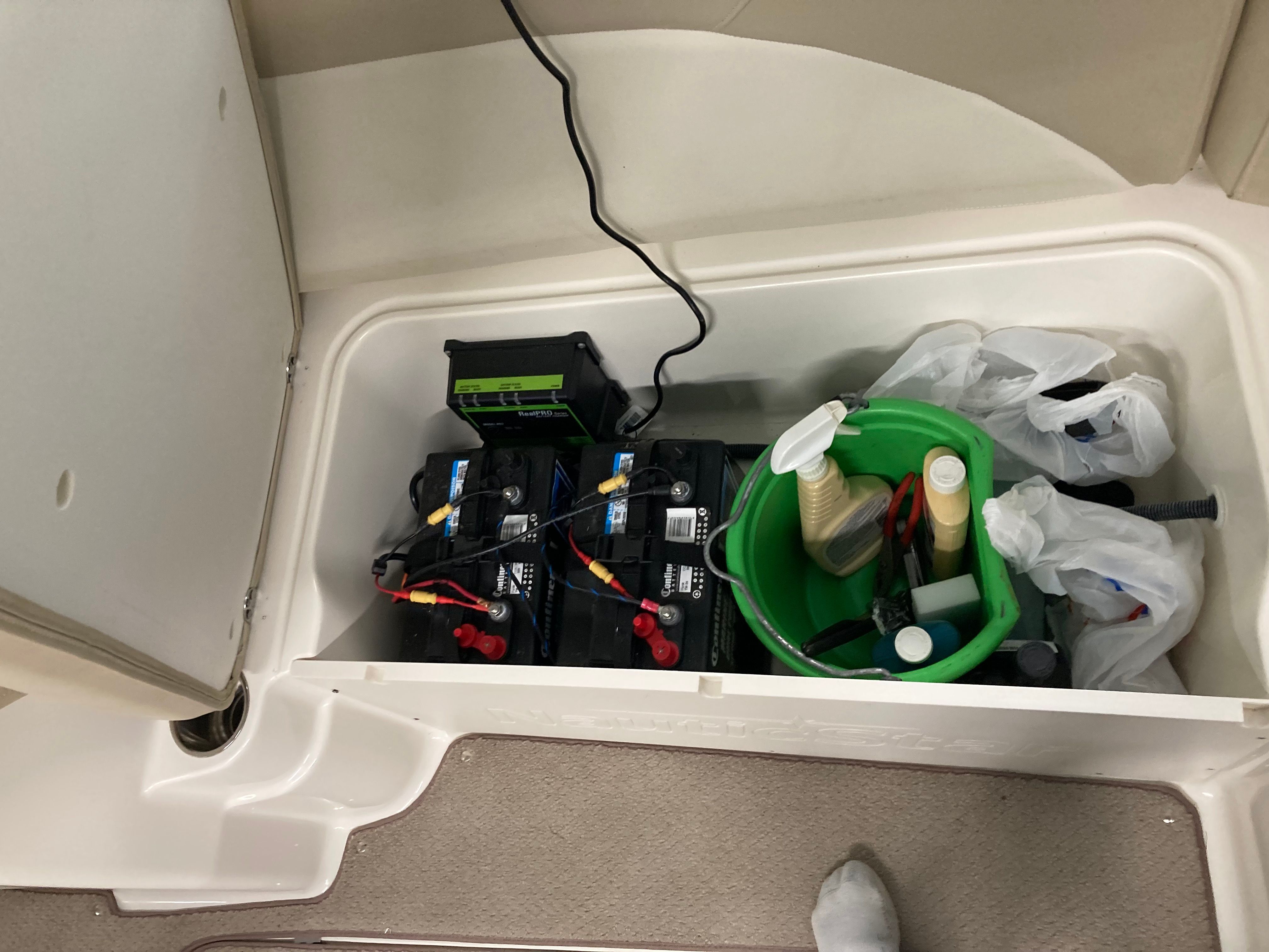 Battery compartment with cleaning supplies and cables.