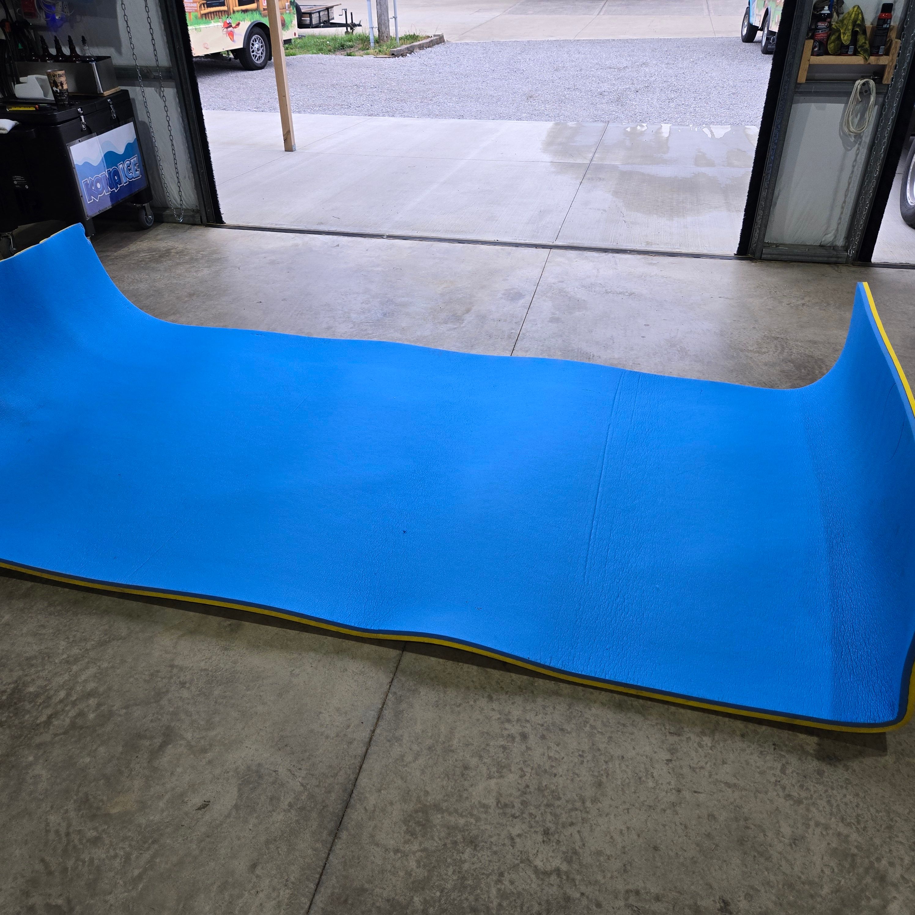 A blue mat lies on a concrete floor in a garage.