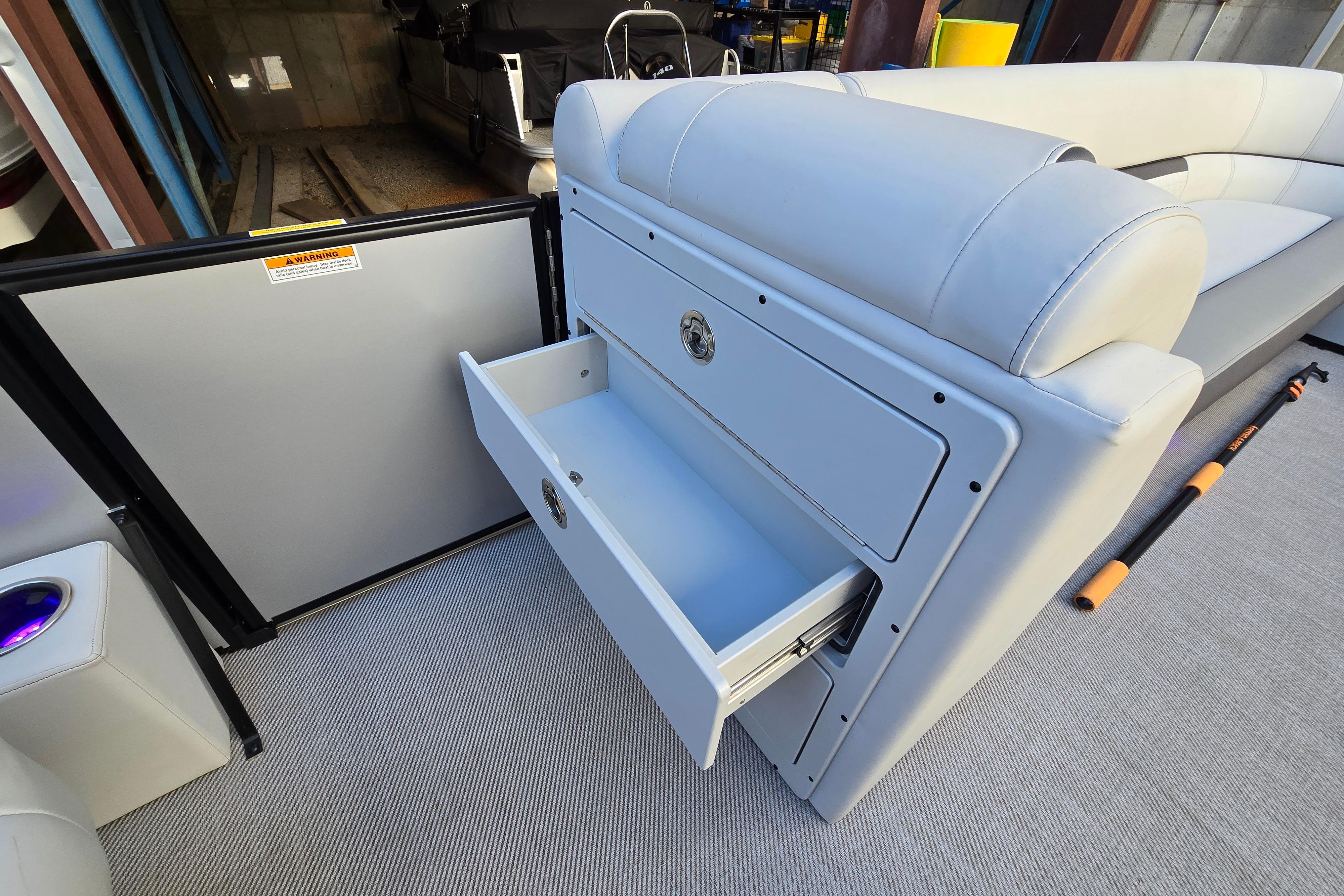 2024 Godfrey Sweetwater 2486 SB boat interior with open storage drawer and seating.