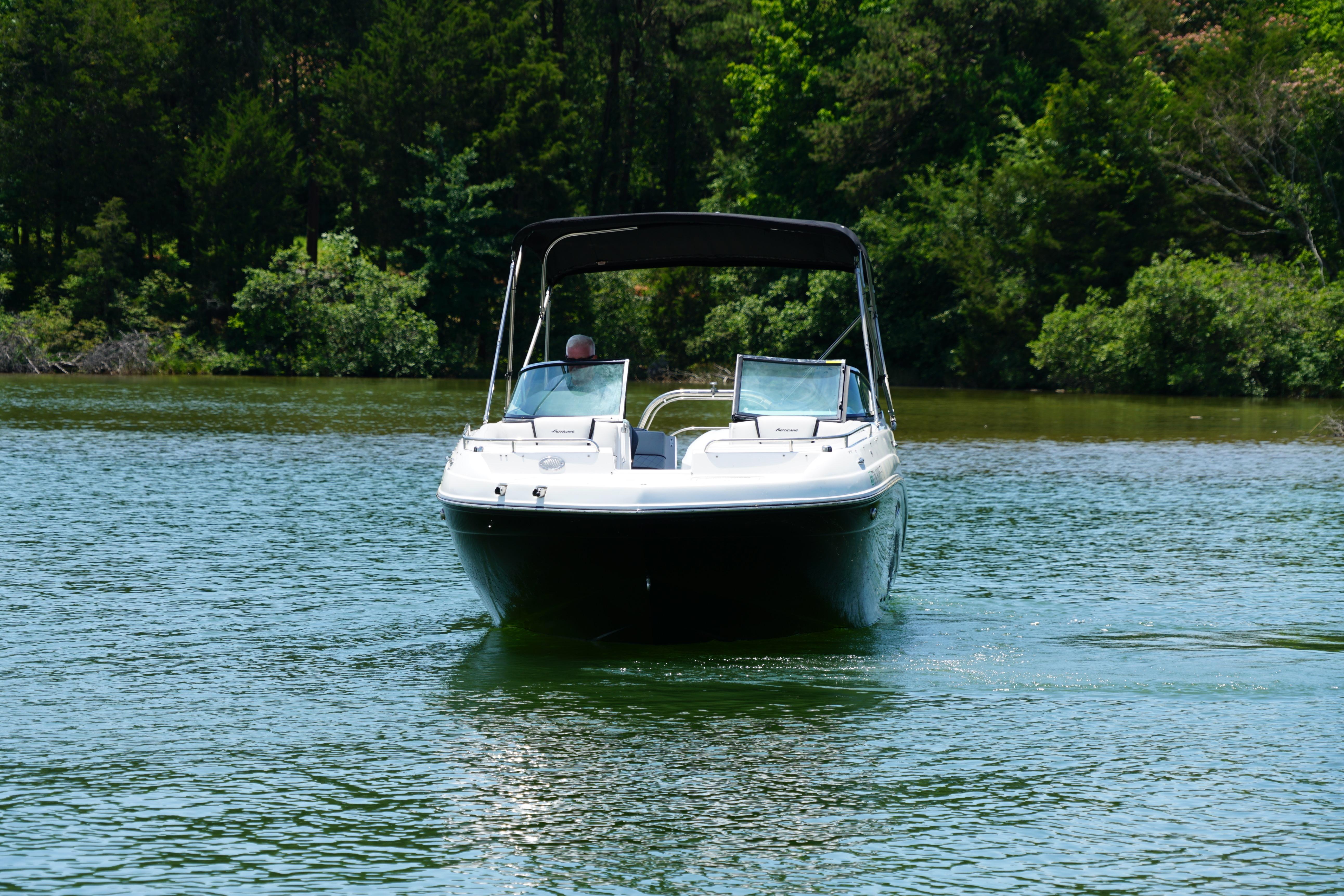 2020 Hurricane SunDeck 2486 OB boat cruising on a serene lake.