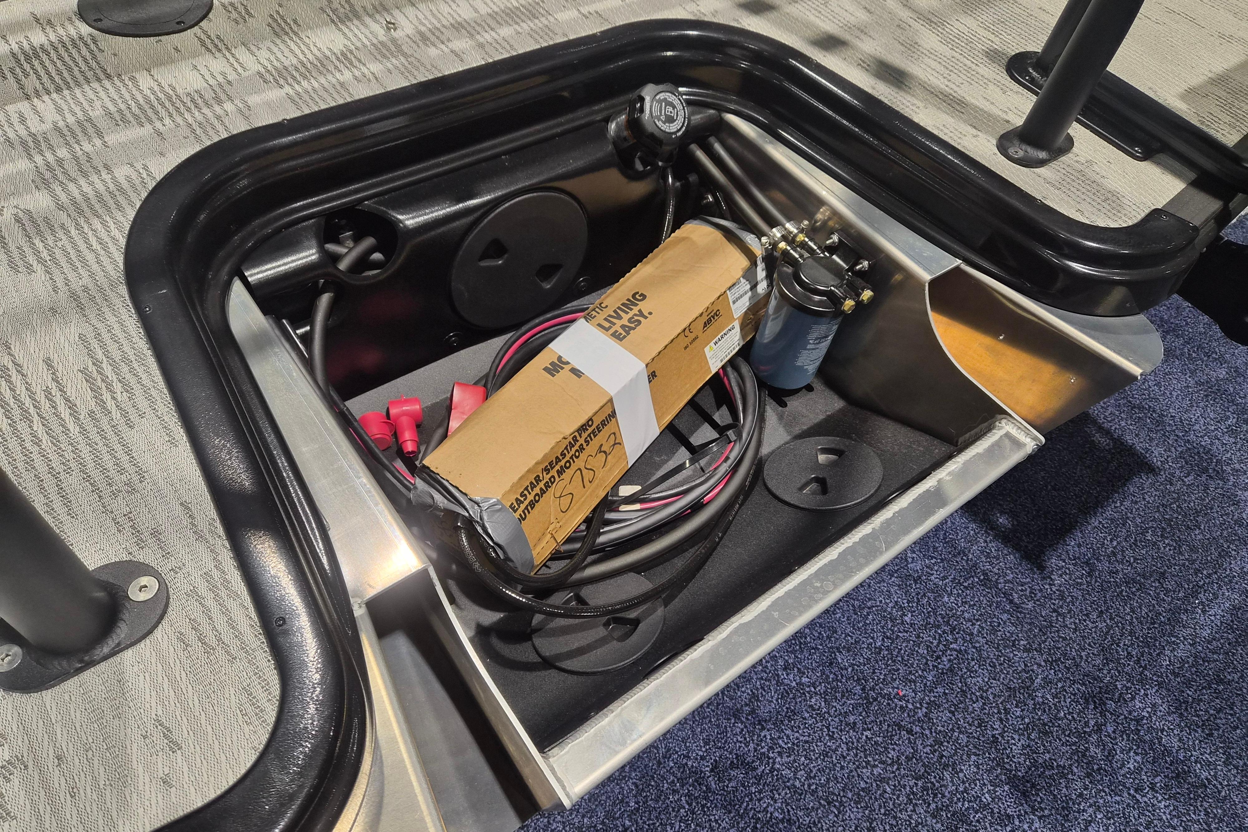 Storage compartment of 2026 Sylvan L3 SLZ boat with cables and a box.
