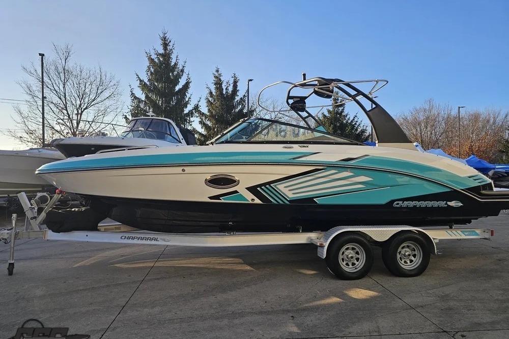 2016 CHAPPARRAL 243 boat on trailer, teal and white design, parked outdoors.