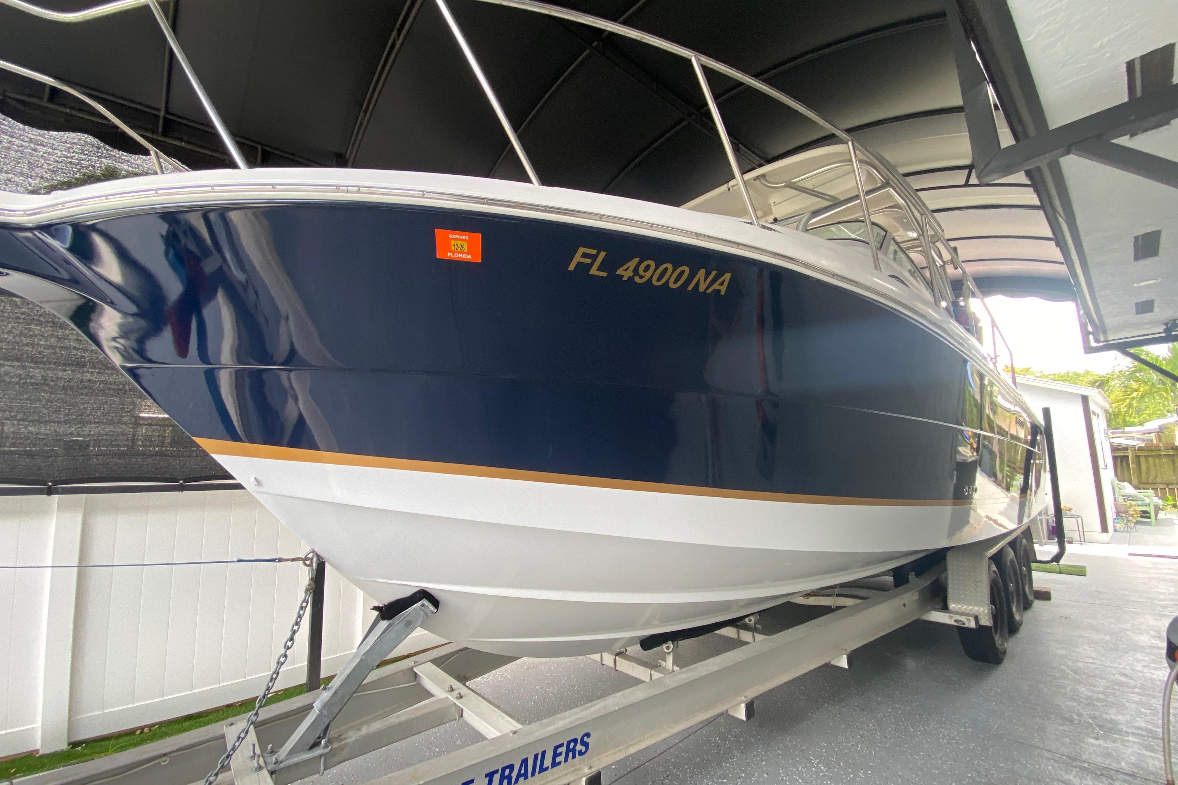 2005 Wellcraft 290 Coastal boat on trailer, blue and white hull, parked under shelter.