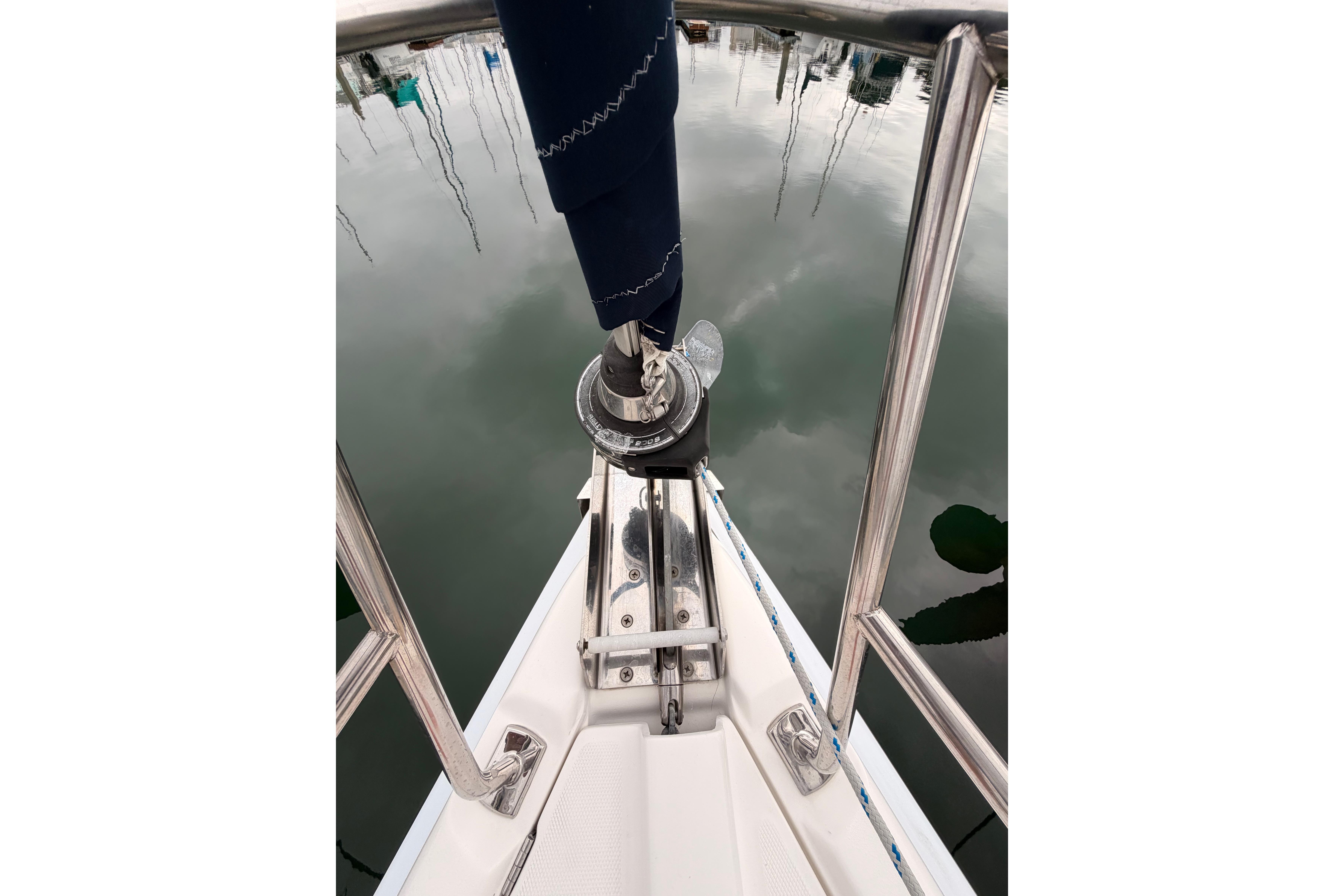 Bow of 2009 Hunter 38 sailboat with stainless steel railing and calm water reflection.