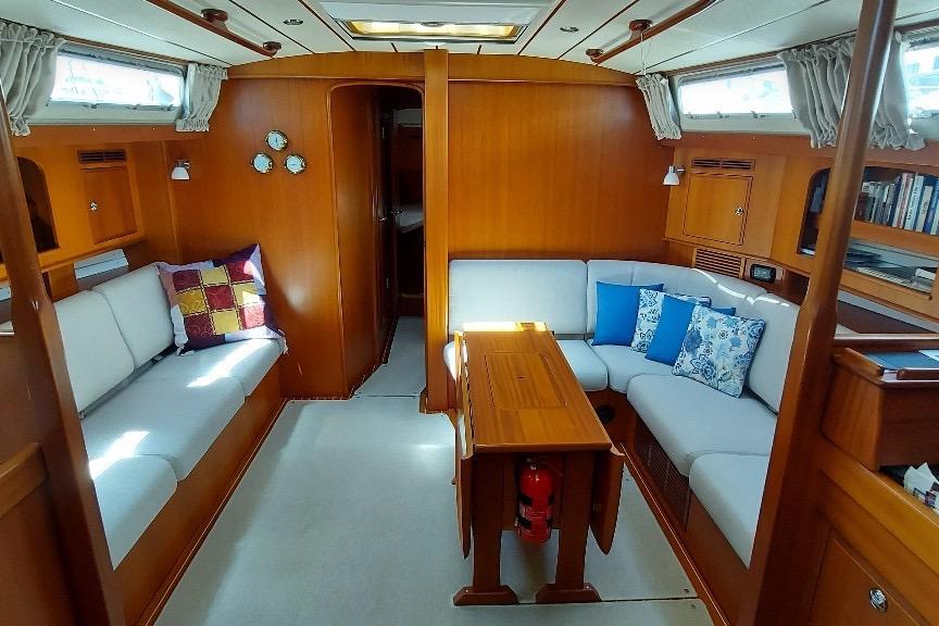 Luxurious 2011 Hallberg-Rassy 48 yacht interior with cozy seating and wooden finishes.