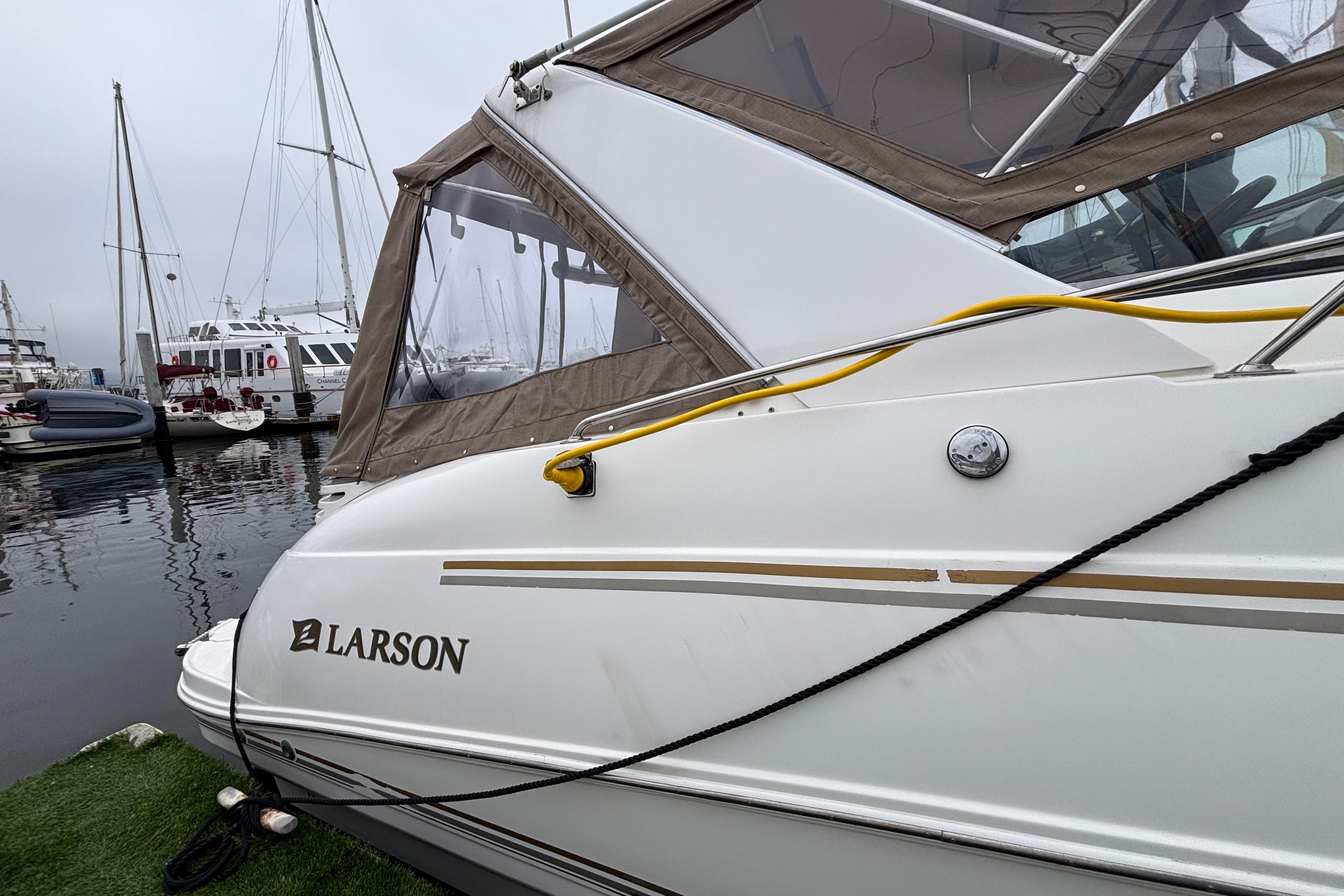 2004 Larson 310 boat docked at marina with other vessels in background.