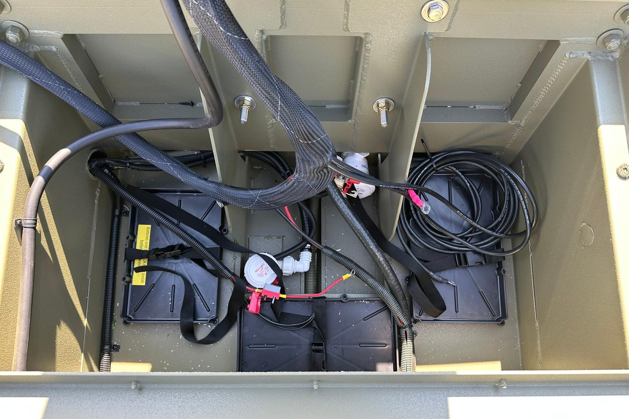 Battery compartment of 2026 Lowe Roughneck 1860SC boat with wiring and cables.