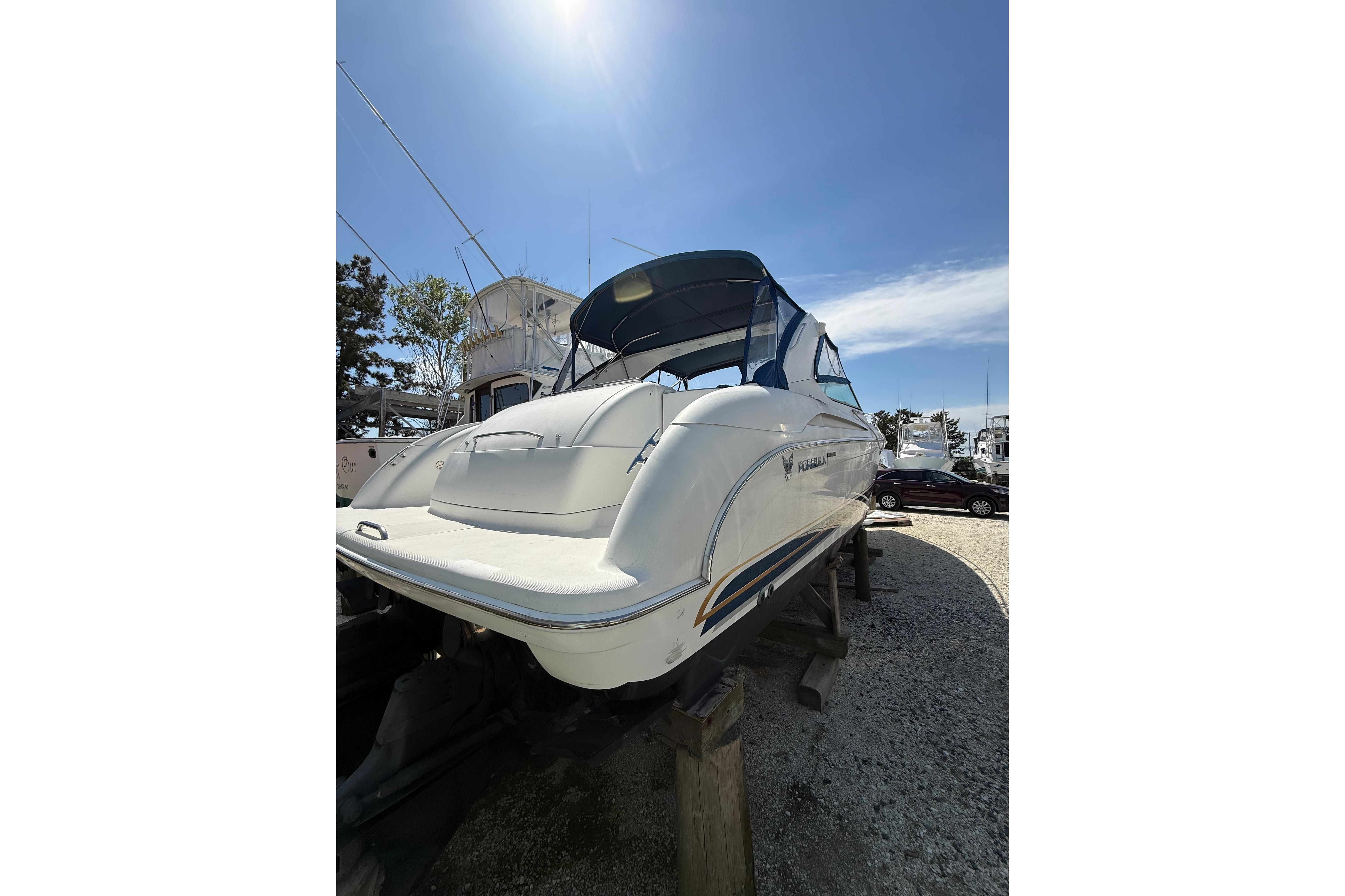 1999 Formula 400 Super Sport boat on dry dock under clear blue sky.