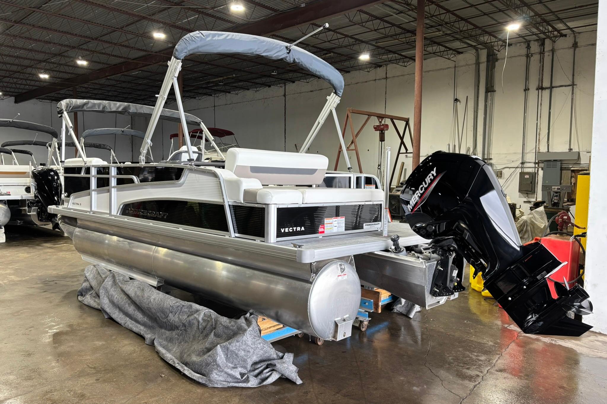 2025 Princecraft Vectra 21 RL pontoon boat with Mercury outboard in a warehouse setting.