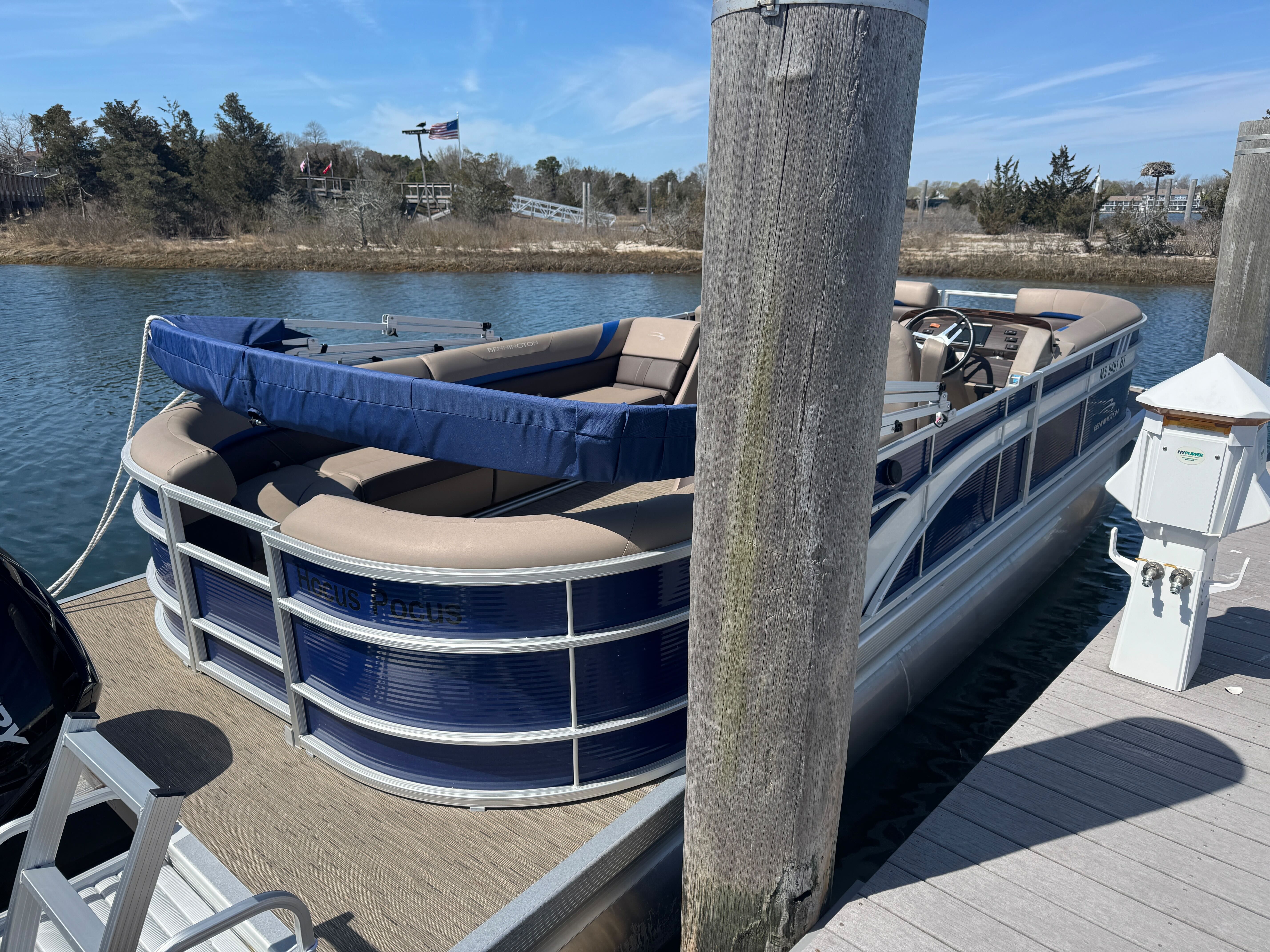 A 2023 Bennington 23SXSRC pontoon boat docked. It features blue and beige upholstery.