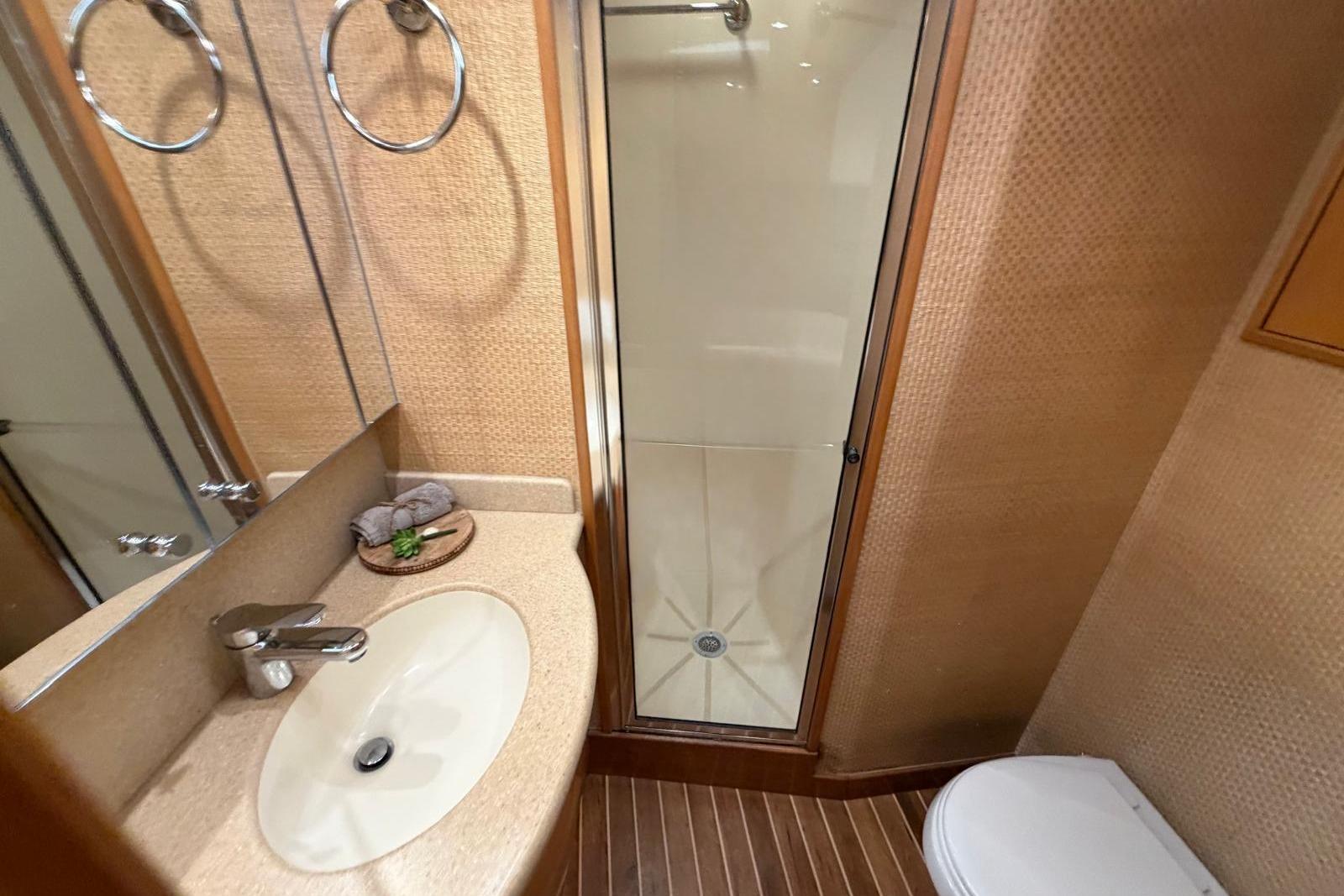 Bathroom interior of 2003 Hatteras 54 Convertible yacht with shower, sink, and toilet.