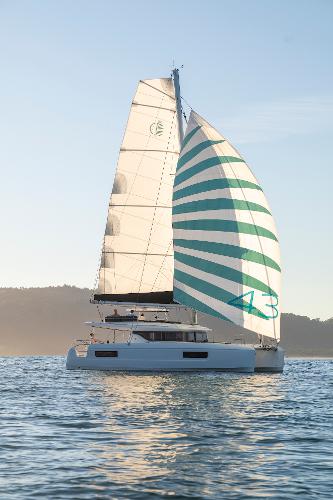 2025 Lagoon 43 catamaran sailing on calm waters at sunset.