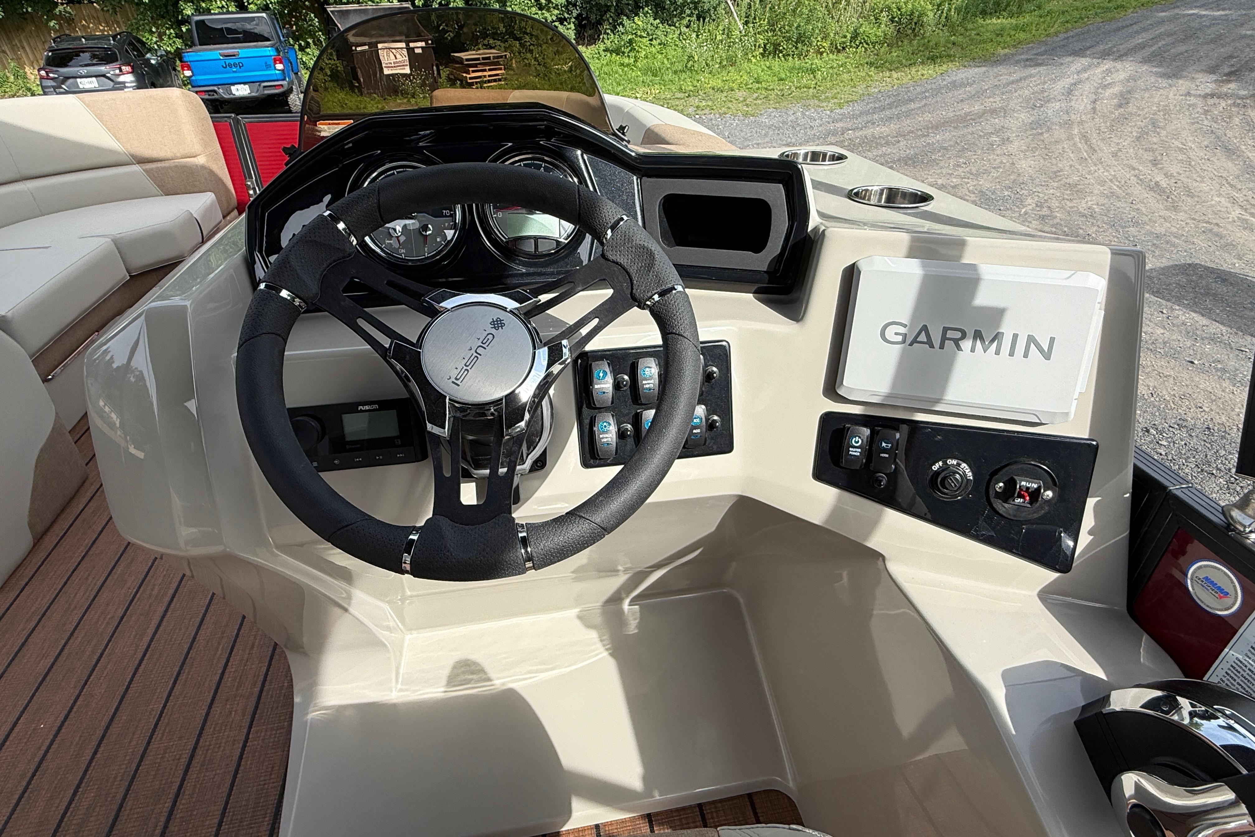 2027 Manitou 21 Aurora LE boat dashboard with Garmin navigation system and steering wheel.