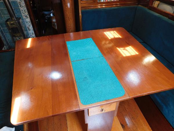 Wooden table with teal runner in a cozy boat interior, 1983 Murray Peterson Coaster III.