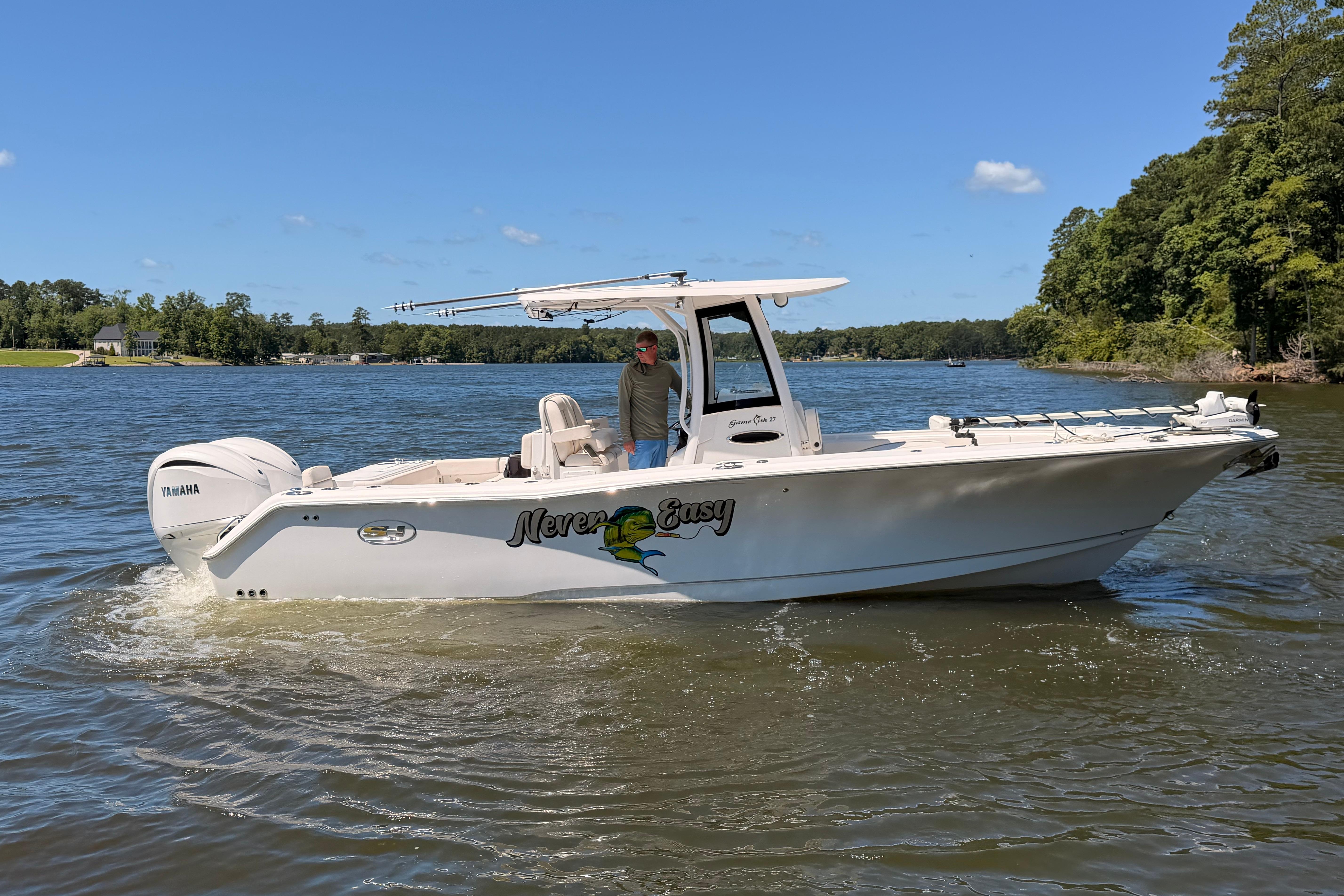 2024 Sea Hunt Gamefish 27 Coffin Box boat on a scenic lake with Yamaha engine.